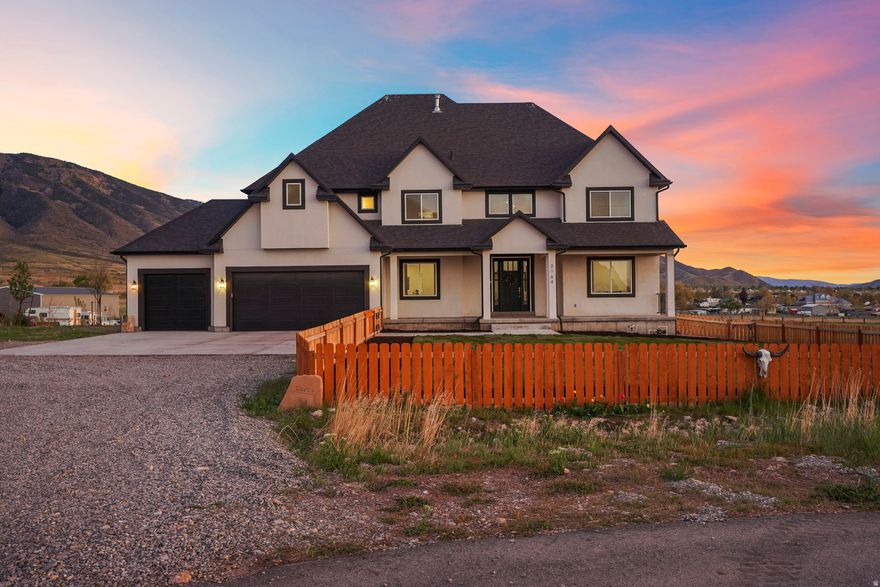 Set on 4.70 acres in the highly sought-after east bench of Tooele, this custom-built home gives you the space, privacy, and freedom that's hard to find while still being just a short drive to the Salt Lake Valley. From the moment you arrive, the fully fenced front yard and welcoming entryway creates an inviting feel. Inside, you're greeted by a functional entry with a built-in bench and hooks, opening to flexible spaces on both sides perfect for a dining room, office, or cozy reading area. The layout just makes sense and flows naturally throughout the home. The kitchen is truly the heart of it all, featuring a large island, tons of cabinetry, access to the large deck, and an additional dining space, with easy access to the main living room with vaulted ceilings that make the space feel bright and expansive. A main-level bedroom and full bathroom add even more flexibility for guests or working from home. Upstairs, you'll find four bedrooms, including a Jack-and-Jill setup and a spacious primary suite with a fully tiled bathroom, separate tub and shower, dual vanities, a large walk-in closet, and private balcony access. The unfinished basement offers 2,165 square feet to grow into. Whether you're thinking a theater, gym, or additional living space, you get that opportunity here to customize. Plus massive cold storage. Step outside and you'll really see what sets this property apart. With 4.70 acres of usable land, you have room for animals, future outbuildings, or just space to enjoy. The backyard is set up for making memories, with an in-ground trampoline, firepit, and a large deck for gathering and relaxing. With over 5,800 square feet and one water share through Lincoln Culinary included, this is more than just a home.. It's a place you can grow into and truly make your own. Buyer and Buyer's Agent to verify all information. Buyer is advised to obtain an independent measurement.