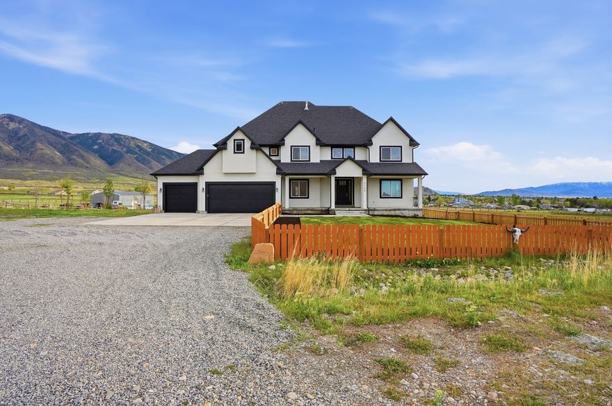 Set on 4.70 acres in the highly sought-after east bench of Tooele, this custom-built home gives you the space, privacy, and freedom that's hard to find while still being just a short drive to the Salt Lake Valley. From the moment you arrive, the fully fenced front yard and welcoming entryway creates an inviting feel. Inside, you're greeted by a functional entry with a built-in bench and hooks, opening to flexible spaces on both sides perfect for a dining room, office, or cozy reading area. The layout just makes sense and flows naturally throughout the home. The kitchen is truly the heart of it all, featuring a large island, tons of cabinetry, and an additional dining space, all open to the main living room with vaulted ceilings that make the space feel bright and expansive. A main-level bedroom and full bathroom add even more flexibility for guests or working from home. Upstairs, you'll find four bedrooms, including a Jack-and-Jill setup and a spacious primary suite with a fully tiled bathroom, separate tub and shower, dual vanities, a large walk-in closet, and private patio access. The unfinished basement offers 2,165 square feet to grow into. Whether you're thinking a theater, gym, or additional living space, you get that opportunity here to customize. Plus massive cold storage. Step outside and you'll really see what sets this property apart. With 4.70 acres of usable land, you have room for animals, future outbuildings, or just space to enjoy. The backyard is set up for making memories, with an in-ground trampoline, firepit, and a large deck for gathering and relaxing. With over 5,800 square feet and water shares through Lincoln Culinary included, this is more than just a home.. It's a place you can grow into and truly make your own. Buyer and Buyer's Agent to verify all information. Buyer is advised to obtain an independent measurement.