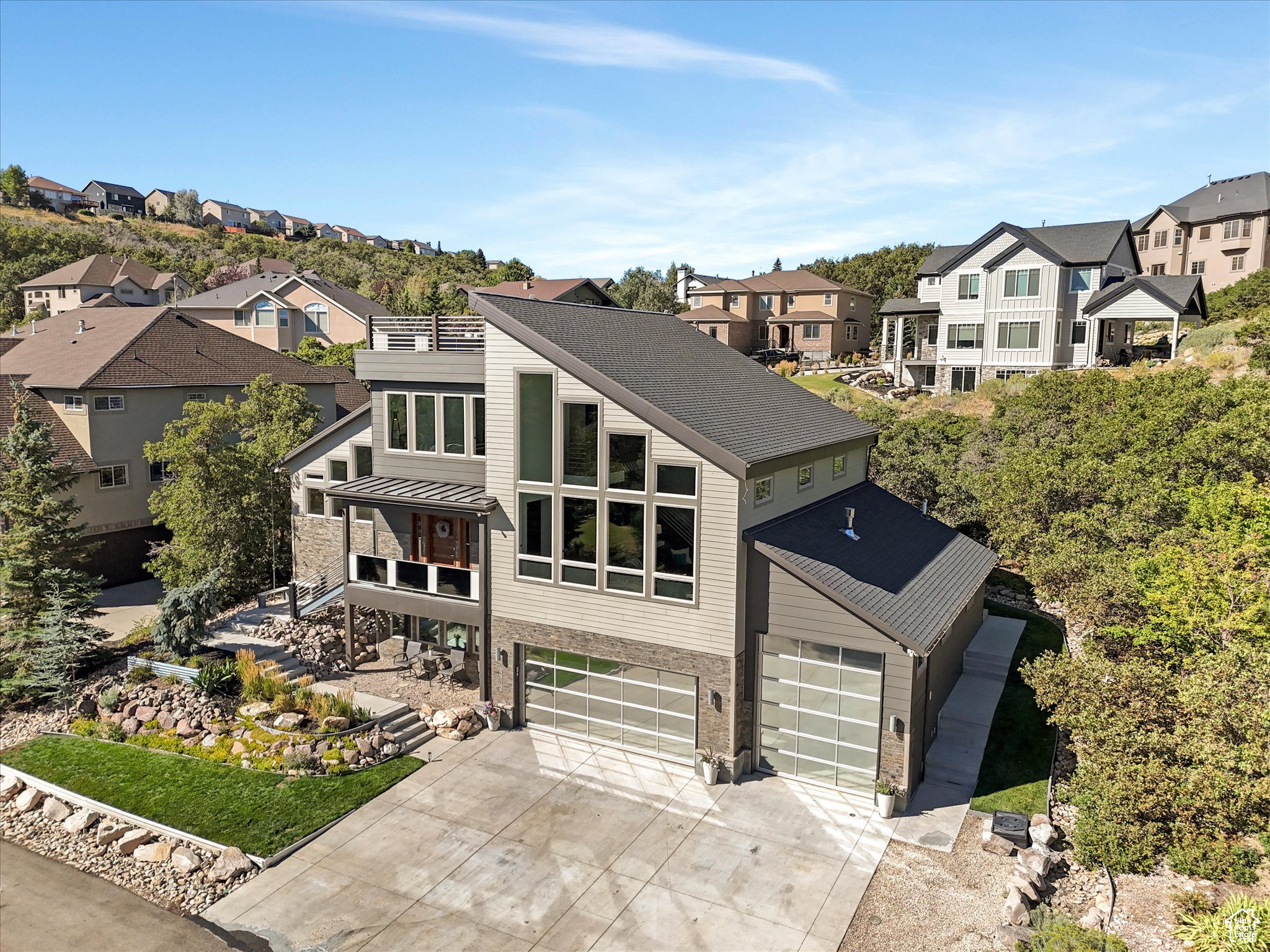 In a sea of sameness, some homes rise above the rest and stand out as truly unique. While sometimes "unique" can mean quirky, there are rare and exceptional homes where "unique" means something special, something extraordinary, and something truly premium. This is that home. Clean lines, bold architecture, and an impeccable layout elevate this home to a whole new tier. Set in SunCrest, the modern design meets the mountain and something about that juxtaposition just works. Step inside and you are immediately met with soaring 26-foot ceilings (you read that right), a floating steel staircase, and windows that frame views so striking they feel like artwork. The family room and kitchen define open concept living, made for gatherings that start with dinner and spill out to fireside chats on the patio. The kitchen itself keeps pace with granite counters, a gas range, and cabinetry that looks as sharp hosting a Saturday night cocktail soiree as it does a weeknight family dinner. The primary suite is every bit a retreat, with 16-foot ceilings, two walk-in closets, and a spa bath featuring a separate jetted tub and shower. Upstairs, two more bedrooms and a full bath keep things flexible for family or friends. Downstairs, the ADU tells its own story. Two bedrooms, a bathroom, a full kitchen, and laundry give it everything it needs to stand on its own, with a private entry from the garage. Perfect for parents, kids, or guests who want their own space. And if you prefer it connected, a simple conversion brings it back into the main home. And then there is the garage. The short version? Room for six or more cars. Over 1,200 square feet of radiant-heated space, built-in storage, and an oversized bay tall enough for your RV or boat. Call it a garage, but it is more like a showroom for whatever you roll in. When it is time to get outside, you will not run out of options. Walk to the clubhouse for a workout or HOA activity, hike or bike the nearby trails, watch the sun drop behind the valley from your rooftop deck, unwind on the covered patio, or circle up around the built-in firepit. Fresh air, endless skies, and a home that stands apart. Rise above the rest of the market, get beyond the greige-ificiation of today's market, and live somewhere extraordinary.