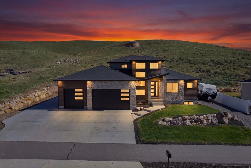 Experience mountain modern elegance in this hillside home by Argyle Homes, featuring breathtaking mountain and lake views and numerous high-end upgrades. Nestled against a hillside, the property offers ultimate privacy with no backyard neighbors. The yard is fully irrigated and thoughtfully designed with a second flat level, perfect for adding a pool, expanding the yard, or creating space for horses or other livestock. The private backyard features a large extended concrete patio with a built-in granite BBQ, creating the perfect space for outdoor entertaining, dining, and gatherings with family and friends.   This property offers exceptional parking  with space for large RVs and additional vehicles. One side features a 35-foot gravel space with full RV hookup, while the other side has a 40-foot cement pad, providing ample parking for all your toys and guests.   Inside, oversized windows fill the home with natural light and showcase the stunning views of the mountains and lake.   The kitchen is a chef's dream, boasting a massive island, abundant soft-close cabinetry, and ample storage. A large walk-in pantry provides even more space for kitchen essentials, while the generous dining area easily accommodates a very large table-perfect for family meals or entertaining guests.  The main-floor primary suite includes a soaking tub, dual sinks, and a separate shower, with laundry conveniently located on both the main level and basement.  The basement features soaring 9-foot ceilings and luxury vinyl plank flooring throughout. It offers a spacious entertaining area, a stylish bathroom with an adjoining laundry space, ample storage, and a mechanical room with a water softener-combining practicality with comfortable, versatile living.   With stunning views, generous yard space, full irrigation, and exceptional parking, this home offers a rare combination of modern elegance, functionality, and privacy.  Included appliances: two washers, two dryers, and the refrigerator, providing convenience and move-in ready functionality.  All information should be independently verified by the Buyer. The current owner has had the home professionally tested and cleared for both meth and radon; copies of the reports are attached for review.