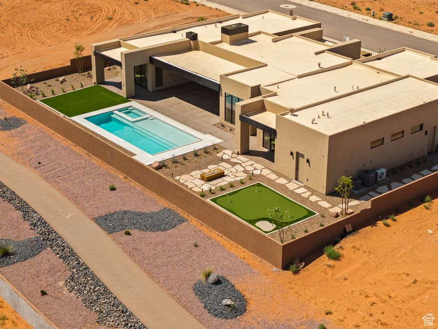 Brand-new 2025 modern desert masterpiece in Sand Hollow Estates with an Amangiri-inspired design and over 3,950 sq ft of luxurious living space. This 4-bedroom, 4.5-bath home blends minimalist styling with exceptional comfort and functionality. Step through a gated courtyard with a custom water feature into a spacious open floor plan highlighted by expansive glass sliders and designer finishes throughout. The chef's kitchen features a professional Signature appliance package, a massive 11-foot island, Taj Mahal leathered countertops, and a full butler's pantry with wine fridge and storage. Retreat to the primary suite with walls of glass, his-and-her vanities and toilets, a freestanding tub, oversized glass shower, and custom walk-in closet with washer/dryer. Each additional bedroom includes its own en-suite bath, with private entrances and courtyards for ultimate privacy. A flex room with beverage fridge and microwave offers versatility for guests or entertainment. Seamless indoor-outdoor living defines this home, with nearly 1,000 sq ft of covered rear patio space, a pool and spa with automatic cover, fire pit, and mini golf with stunning east-facing orientation for year-round enjoyment. Additional highlights include: -38-ft boat garage plus oversized 2-car garage with epoxy flooring -3-sided custom fireplace with textured plaster surround -Designer tile and lighting throughout -Energy-efficient construction with tankless water heaters, blown-in insulation, and Low-E glass windows -Smart home pre-wire for security, audio, automatic shades, and more The HOA fee includes full yard maintenance, access to 3 pools, 2 hot tubs, a fitness center, and 2 pickleball courts. Residents also enjoy live music events and annual community celebrations like the Car Show, Sky Fest (Hot Air Balloon Festival), and the Pioneer Day Celebration. Residents also receive discounts and VIP access to golf, events, and UTV and watercraft rentals. Located minutes from Sand Hollow Reservoir and championship golf, this home offers unmatched luxury and lifestyle in the heart of Southern Utah.