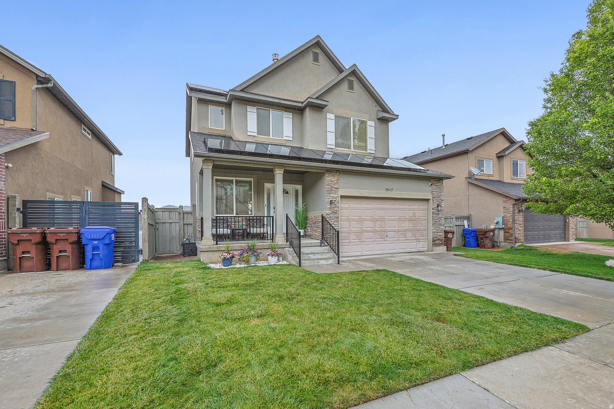 Two-story stucco exterior featuring stone accents, a covered front porch, an attached garage, and a concrete driveway