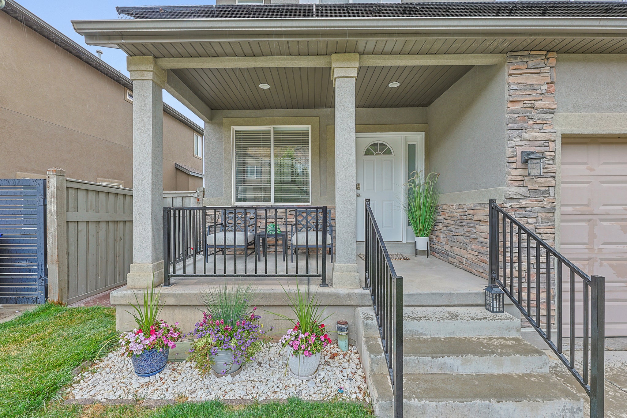 Covered front porch with concrete steps and black metal railings
