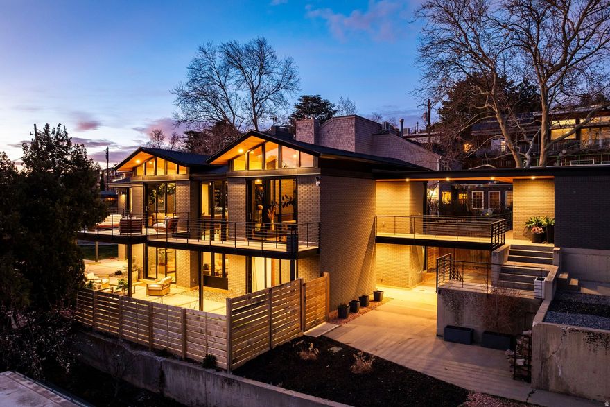 Ralph Evans set the architectural foundation for this residence, later refined by Guymon Properties into a home that feels both intentional and undeniably expressive. It's a space where design isn't just observed, it's experienced. From the moment you arrive, the architecture commands attention. Strong, deliberate lines meet expanses of steel and glass, softened by a palette that allows light to become the defining element. The home doesn't simply open to its surroundings, it curates them, framing each view with precision. Inside, the experience unfolds with a quiet intensity. Natural light moves effortlessly through the space, shifting the mood from morning to evening and bringing every surface to life. At its center, a sculptural bridge and steel staircase create a striking focal point, suspended like a runway through the heart of the home. It's both architectural and cinematic, a feature that invites movement, perspective, and presence. There's a rhythm to the way the home lives. Mornings feel elevated and intentional. Coffee in hand, sunlight pouring in, the space feels calm, focused, almost meditative. By evening, the energy softens into something more intimate. Music carries differently here. Conversations linger. The home adapts effortlessly to both solitude and connection. The primary suite is a true retreat. Clean lines, refined finishes, and a sense of calm define the space, complete with a generous walk-in closet and a spa-like bath featuring elevated materials and heated floors. Just beyond, the transition to outdoor living feels seamless. The backyard has been transformed into a private, resort-style escape. A newly added swimming pool anchors the space, while the outdoor kitchen sets the stage for long, unhurried summer nights. Whether hosting or unwinding, the experience feels elevated yet effortless. Every detail throughout the home has been considered, creating a balance of bold architecture and livable warmth. It's a space that feels grounded, but never ordinary. Positioned along one of the most desirable streets in the Avenues, the location offers immediate access to downtown, nearby trail systems, and the unmistakable character of one of Salt Lake City's most iconic neighborhoods. This is more than a home. It's a statement in design, a study in light, and a lifestyle that unfolds with intention.