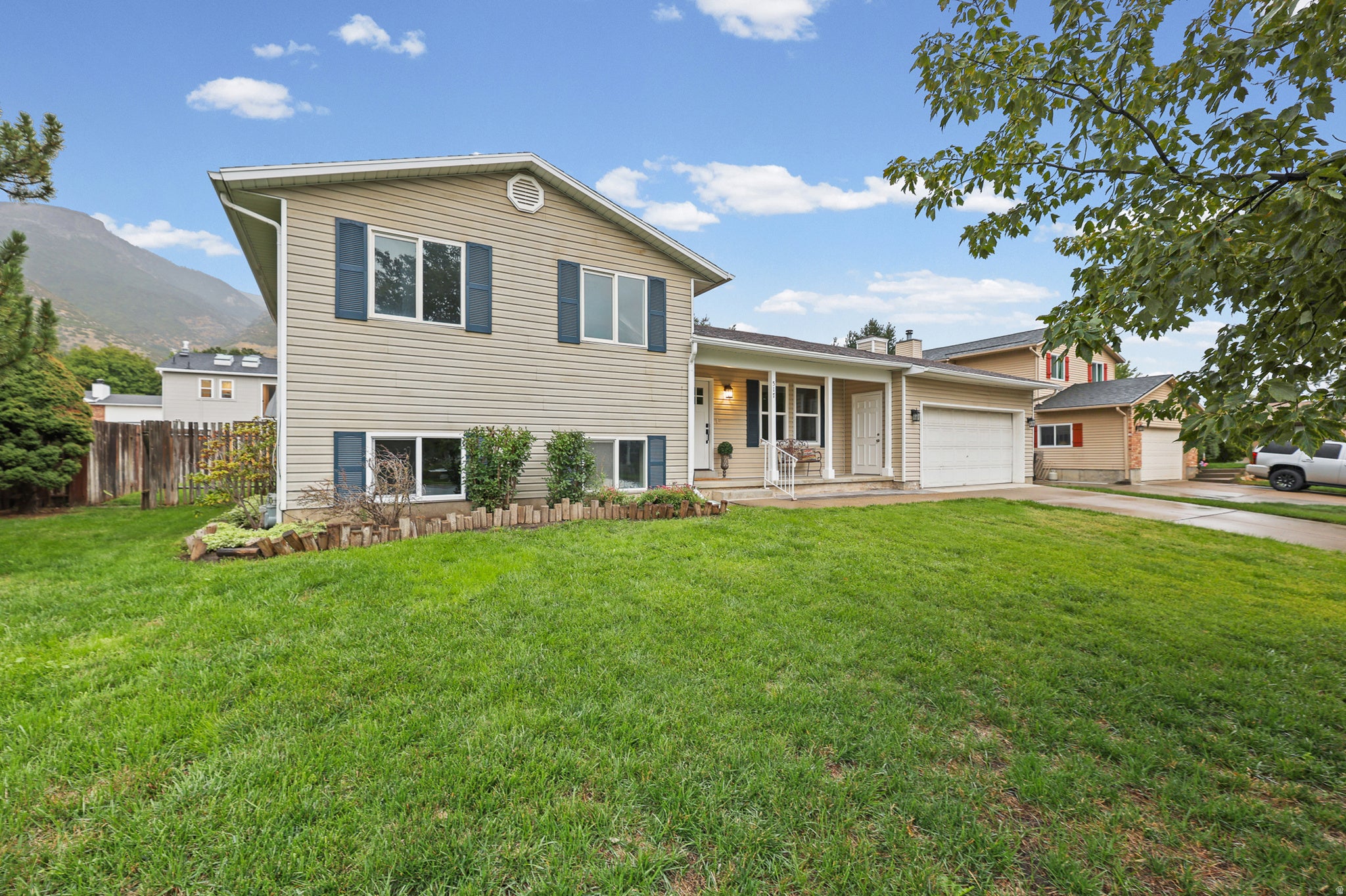 Two-story siding exterior with dark shutters, covered front porch, and an attached garage