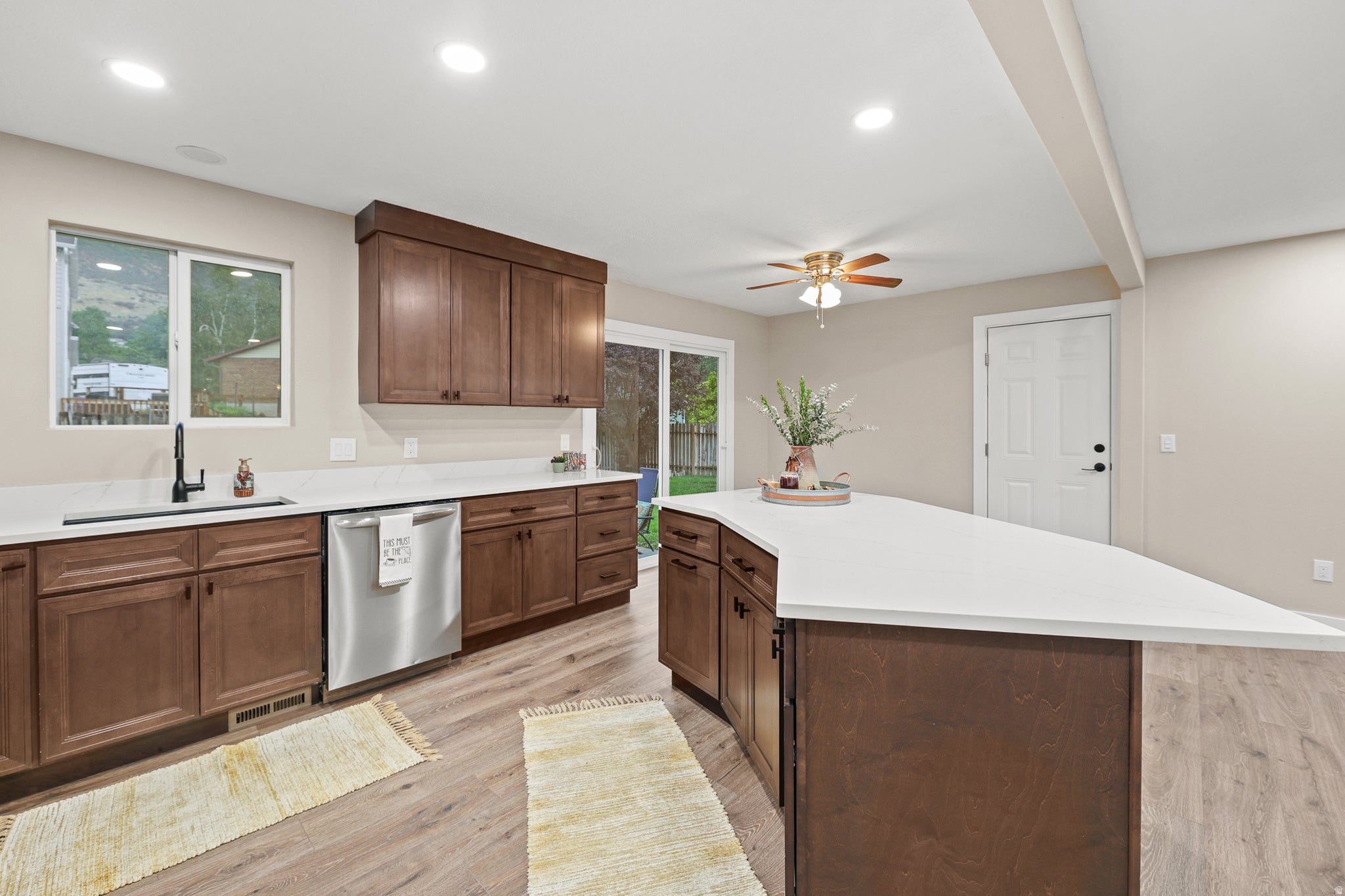 Kitchen featuring wood-finish cabinetry, light countertops, stainless steel appliances, and wood-like flooring