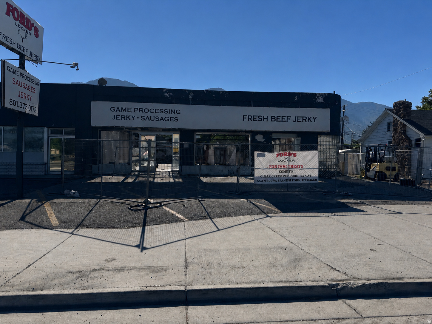 Commercial building featuring a flat roofline and visible signage, with a partial concrete parking area and sidewalk