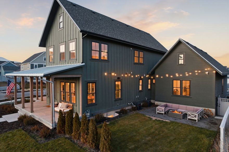 This home was built by Rainy Homes (Daybreak's Top Luxury Builder). It sits on a .20-acre corner lot directly across from Pennant Park and one block from the Watercourse in a prime Daybreak location and was built in 2023 with 5,119 square feet and extensive upgrades throughout. The kitchen features premium Monogram appliances, a slide-in 8-burner gas range with griddle, built-in full-size refrigerator and freezer, and a butler's pantry with inset cabinetry, microwave, open shelving, and recessed lighting, while coffered ceilings highlight the entry and family room. The primary suite includes a spa-style bath with dual shower heads, soaking tub, and dual walk-in closets. The finished basement offers 10-foot ceilings and includes a custom gym, kids' playhouse, and lap-wood accent wall. Exterior features include a wrap-around porch with metal porch covering, upgraded farmhouse-style gutters, and 10-foot-deep cold storage beneath the porch. The oversized 4-car garage offers extra height and a 240V EV outlet. Additional features include dual furnaces, dual water heaters, water softener, smart lighting, fireplace and garage controls, smart sprinklers and drip irrigation, security cameras, Eufy doorbell, interior and exterior speakers, and a fully landscaped, fenced yard with an in-ground trampoline, all located close to trails, parks, pools, and Daybreak amenities.