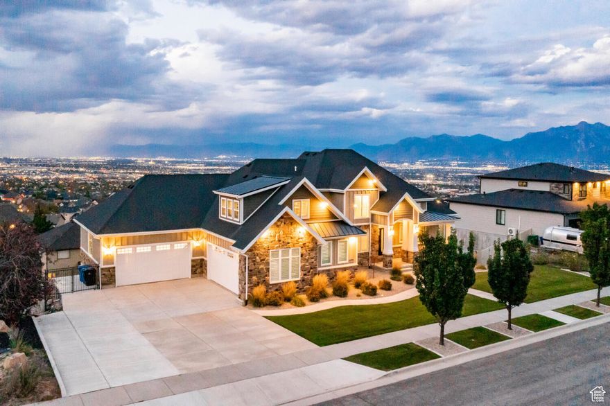 Situated atop the most prominent ridge in the highly exclusive Lookout Ridge community, this residence boasts breathtaking, unobstructed panoramic views of the entire valley from nearly every corner of the house. Crafted with the intent of transforming your living space into a tranquil sanctuary, this home is brimming with distinctive features that set it apart. Prepare to be awestruck by the chef's kitchen, which boaststop-of-the-line Thermador appliances such as agasrange, double built-in ovens and microwave, a floor-to-ceiling wine and beverage fridge, built-in refrigerator, and ice maker. The custom solid wood cabinets are loaded with premium features, and the white quartz and black granite countertops complement each other perfectly. A hidden butler's pantry with a discreet exit to the garage makes unloading groceries a breeze. The main floor is designed for seamless living and entertaining, featuring stately two-story coffered ceilings in the family room, an open loft upstairs, and a massive covered deck. The master suite is fit for royalty, complete with coffered ceilings, a spa-like bathroom featuring a charming soaker tub (don't miss the chandelier and brick wall), a stunning walk-in shower, separate sinks with gorgeous marble countertops, and two spacious walk-in closets. The repurposed antique dresser in the half-bath is a charming touch that's sure to delight. The laundry room is spacious and well-appointed, with ample folding counter space and plenty of storage. It opens to the mudroom and has a second exit to the garage. The elevator shaft is framed and wired for future handicap access, and the current closets on all floors can be repurposed as needed. The first basement includes a full mother-in-law apartment (ADU)with a private interior entrance to the spacious four-car garage and an additional covered deck. The bottom basement houses a full two-story indoor sport court, gym, bedroom/office/flex space, and theater room, with a walkout to a fully landscaped backyard complete with a custom gas fire pit and a large RV pad. This home was built to last, with commercial-grade framing, fire and earthquake-proofing, and interior automatic sprinkler systems. It was crafted with the utmost attention to detail to create a forever home that will stand the test of time. Located just steps away from hiking and mountain biking trails in Rosecrest and paddleboarding and kayaking at Blackridge Reservoir, this home offers the perfect balance of seclusion and convenience. You'll be just far enough away from the hustle and bustle of the city, while still enjoying easy access to all the amenities via Mountain View Corridor, including Mountain View Village, Real school and practice stadium, and Providence Hall charter schools. A quick 30 minute drive will get you to the base of the Cottonwood Canyons, Downtown SLC, and the Salt Lake International Airport. Furnishings can be included with an appropriate offer. Enjoy creating memories in this exceptional home - you may never want to leave! Welcome to your new crib!