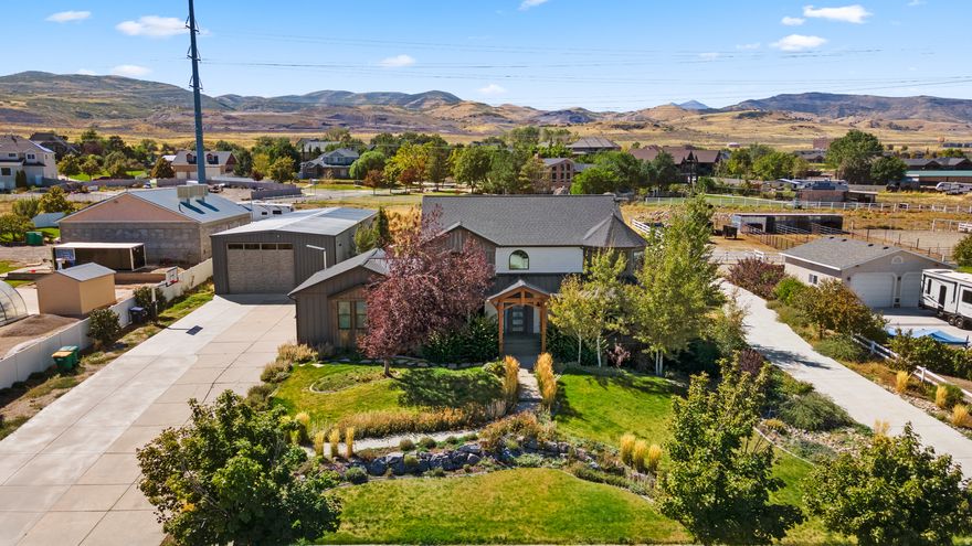 Welcome to an extraordinary modern-farmhouse residence, masterfully reimagined with sweeping views of the Wasatch Mountains. Completely remodeled with uncompromising attention to detail, this home showcases refined craftsmanship, timeless design, and resort-level amenities at every turn. A sweeping wraparound covered front porch sets a gracious tone, offering a front-row seat to peaceful mornings and unforgettable mountain sunsets. Inside, the home unfolds into light-filled living spaces anchored by a striking living room with oversized new windows, creating an atmosphere of warmth, elegance, and effortless comfort. The heart of the home is the chef's kitchen-designed to impress and perform-featuring custom two-tone cabinetry, quartz countertops, a grand statement island, pot filler, double ovens, stainless steel appliances, and abundant storage. Updated LED lighting throughout enhances the home's clean lines and sophisticated finishes. The primary suite is a true private retreat, offering generous space, automatic blinds, and a grand custom bathroom suite complete with glass-enclosed shower doors, upscale finishes, and an expansive walk-in closet designed for luxury living. Outdoors, the property transforms into a private resort. A newly constructed in-ground saltwater pool with cascading waterfall features and multi-level lounging areas creates a stunning focal point, complemented by a chic pool house ideal for entertaining or relaxing. Two covered decks provide ample space for gatherings, while low-maintenance turf grass, an in-ground trampoline, and a private basketball court with custom lighting elevate both form and function. Zoned for horses, this property offers a rare opportunity to blend refined living with equestrian potential, adding versatility and long-term value to an already exceptional setting. For the collector, entrepreneur, or enthusiast, the impressive 15-car heated and air-conditioned garage and shop is unparalleled, featuring massive automatic doors and expansive concrete space ideal for oversized vehicles, business use, or luxury storage. Additional RV parking adds further versatility. This is more than a home-it is a lifestyle property where modern sophistication meets refined rural charm. Every element has been thoughtfully curated to offer privacy, luxury, and enduring value in a setting that is as functional as it is breathtaking.   Square footage figures are provided as a courtesy estimate only and were obtained from county record. Buyer is advised to obtain an independent measurement.