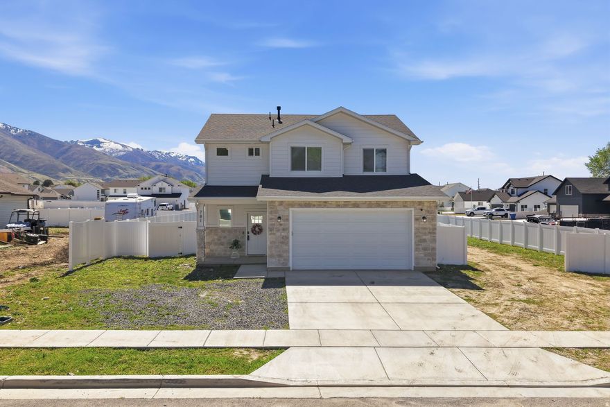 Nestled against the stunning backdrop of the Wasatch Range, this 2024-built home delivers the perfect blend of modern craftsmanship and everyday comfort. Snow-capped mountain views greet you from the moment you arrive, while the generous fenced lot - complete with RV access - offers all the space you need to spread out, entertain, and store your toys. Step inside to an open-concept main level where LVP hardwood-style flooring flows seamlessly from the bright living area into the heart of the home - a beautifully appointed kitchen featuring rich knotty alder cabinetry, quartz countertops, a center island with bar seating, stainless steel appliances, and a walk-in pantry. Whether you're hosting a dinner party or a quiet weeknight meal, this kitchen is ready for it all. The craftsman-style staircase - with warm wood newel posts, wrought iron balusters, and plush carpet treads - makes a statement as it leads you upstairs to the private sleeping quarters. The primary suite is a true retreat, complete with a ceiling fan, walk-in closet, and a private ensuite bathroom featuring a tiled walk-in shower with a black-framed glass door, quartz vanity, and matching matte black fixtures. Three additional bedrooms and two full bathrooms provide plenty of room for family and guests. Thoughtful details are found throughout - recessed lighting, modern ceiling fans, crisp white shaker-style doors with black hardware, and a consistent design language that feels fresh and intentional. The attached two-car garage, full white vinyl fencing, and wide concrete driveway complete this turnkey package. This growing Brigham City neighborhood is Northern Utah living at its finest. No waiting on new construction - just move in and enjoy.
