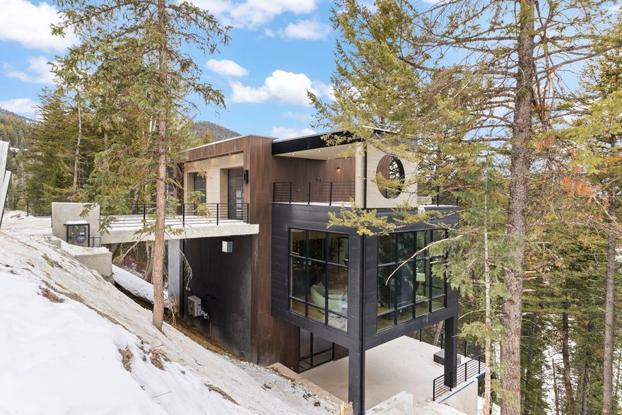 Experience a rare offering in Park City - a newly constructed mountain modern residence designed to elevate everyday living through thoughtful architecture, privacy, and extraordinary views. Set on over one acre in Summit Park and approved with a coveted 55-foot height variance, this four-level home is unlike anything else currently available in the area. A private elevator connects all four floors, allowing effortless access to expansive living spaces and breathtaking mountain and forest views from nearly every level. Surrounded by mature pines, the home is designed to embrace its natural setting with over 1,500 square feet of decks and balconies, creating seamless indooroutdoor living year-round. Located just minutes from world-class skiing and steps from Park City's premier hiking, mountain biking, and cross-country ski trails, the home offers both convenience and a true sense of retreat. The interior features custom finishes throughout, including top-of-the-line appliances, designer plumbing and lighting fixtures, smart home technology, and expansive floor-to-ceiling windows that frame the surrounding wilderness. Every space has been intentionally designed - from reading nooks and private office areas to an outdoor kitchen ideal for entertaining and a striking custom fireplace that anchors the main living area. The primary suite serves as a private sanctuary, complete with a spa-inspired bathroom and its own balcony overlooking the trees. Additional bedrooms and flexible living spaces provide comfort, privacy, and versatility for family and guests. This home represents a rare opportunity to own a newly built, architecturally distinctive residence in an established Park City setting - offering modern luxury, privacy, and access to the lifestyle that defines mountain living.