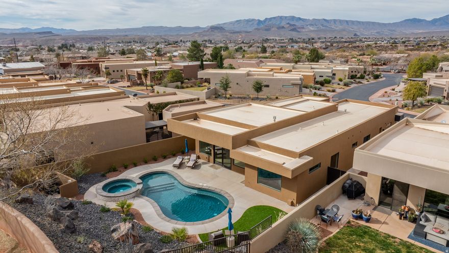 Located within the Tuweap community, a private gated neighborhood near Snow Canyon State Park, this thoughtfully designed home offers a refined blend of modern architecture & relaxed indoor-outdoor living. Inside, white oak wood floors, custom cabinetry, and quartz countertops set a sophisticated yet welcoming tone. Kitchen features an expansive island, generous storage, & a layout designed to flow effortlessly into the main living space. Architectural ceiling details, built-in shelving, and a spectacular fireplace that anchors the living space & defines the architecture of the room adding depth and character throughout. Primary suite is a private sanctuary, offering a spa-inspired bath, dual vanities, freestanding soaking tub, oversized walk-in shower, & custom walk-in closet designed for both beauty & organization. Private backyard is anchored by a sleek in-ground pool and elevated spa, framed by desert landscaping & covered patio space that invites year-round enjoyment. Large sliding doors create a seamless transition between interior living areas and the outdoor retreat, making this home equally suited for quiet evenings or entertaining. Enjoy a peaceful setting with convenient access to scenic trails, red rock landscapes, and the outdoor lifestyle that defines Southern Utah.