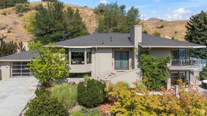 Stylish and sharp modern home at the top of Terrace Hills with wide open valley, mountain and city views! This unique floor plan offers functional daily living and ideal spaces for entertaining. Main floor primary bedroom suite has an oversized walk in closet with built in cabinets and drawers, plus a washer/ dryer connection. Newly refinished bamboo flooring throughout, fresh and clean white walls on the main floor, lots of natural light including a neat curved walls of windows that brings the views inside both the main and lower levels, glossy black kitchen cabinets with bar seating that is open to the living and dining room, access to the south facing covered deck to sit and admire the private, quiet hillside and views! Lower level has 3 bedrooms, wet bar area and sitting room, family room, storage and 2 bathrooms. There are two attractive gas fireplaces. The yard has been professionally designed and installed with natural landscaping full of trees, bushes and grasses that emphasize the mountainside landscape. Hot tub, patios, red rock water feature really make this private yard stand out! Walk to Bonneville Shoreline trail. Only minutes to downtown, the U of U, airport and many outdoor attractions!