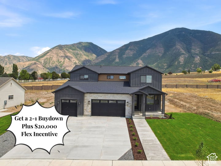 Modern two-story residence featuring a dark gray siding and stone facade, a two-car garage, and a covered entry porch