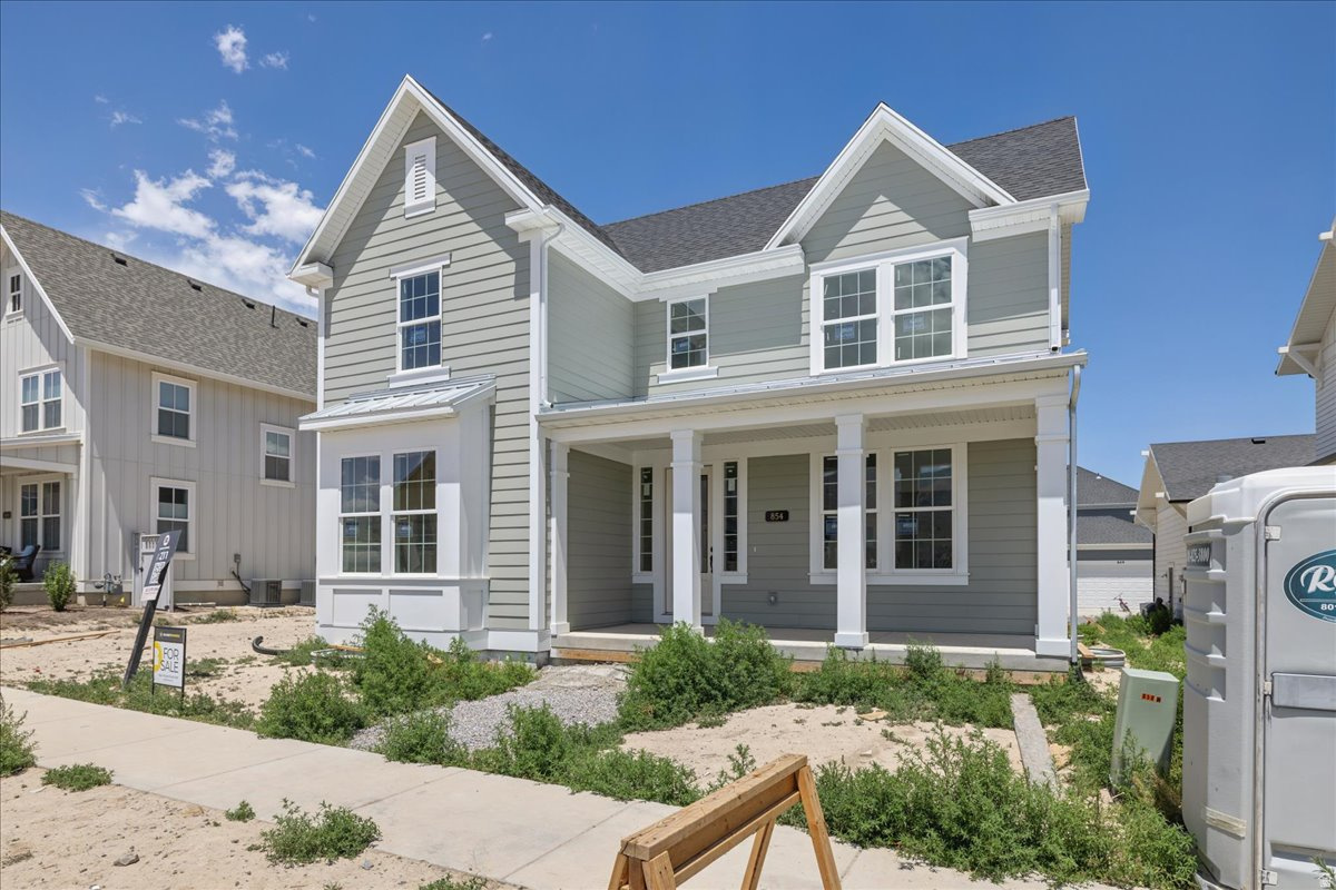 Two-story residence featuring light gray horizontal siding, white trim, a covered front porch with white columns, a bay window with white trim, and a gabled roofline