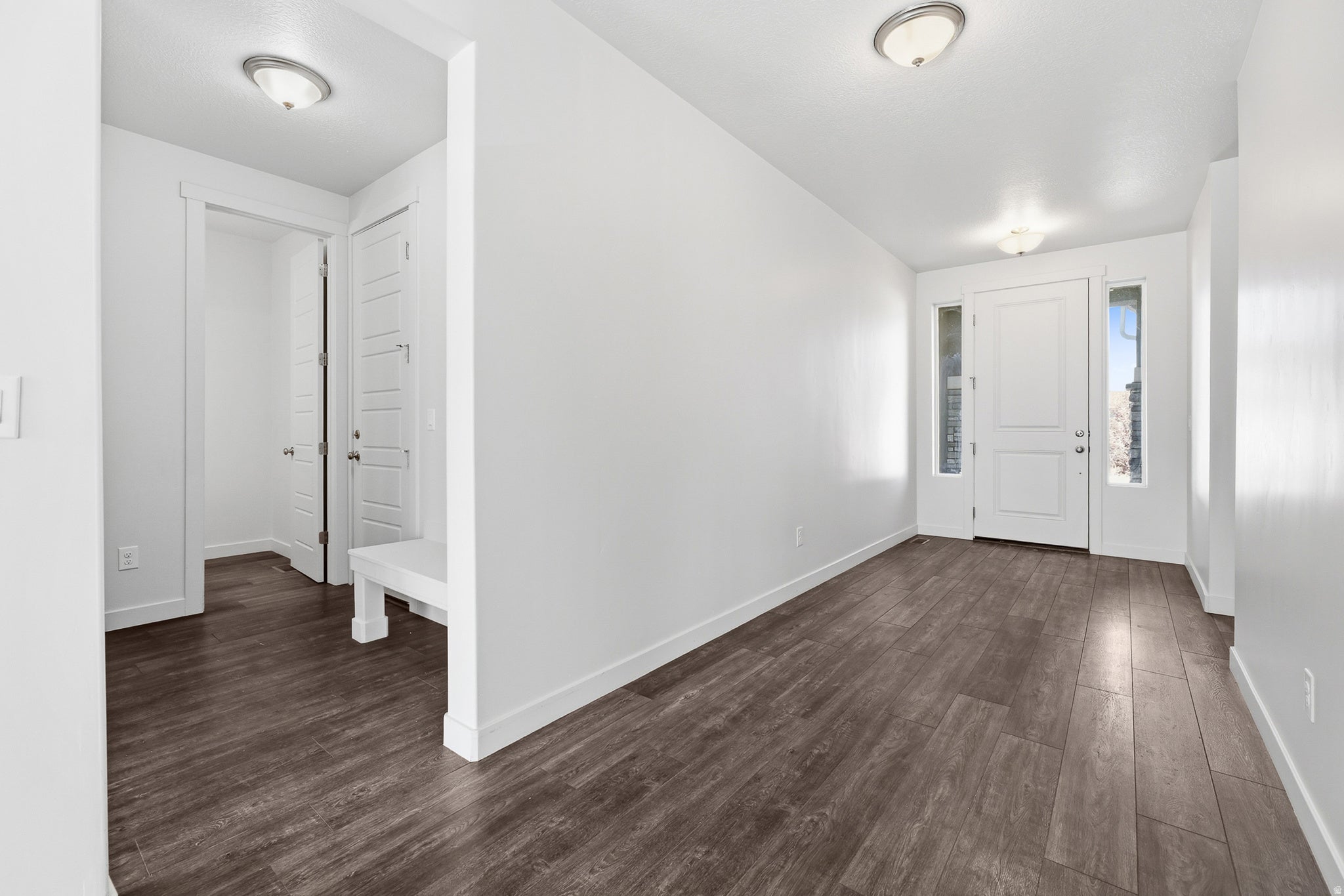Entryway featuring wood-finish flooring, a solid panel front door with side lites, recessed lighting, white trim, and a built-in bench