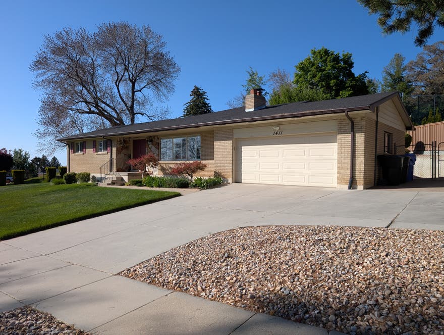 Perched on the prestigious high east bench of Bountiful, this well-maintained residence is offered for the first time by its original owner. The home opens with a spacious, light-filled living room that transitions naturally into the heart of the main level. Here, a large kitchen with ample cabinetry serves as a functional hub, flanked by a formal dining room and an expansive family room that was added to the home in 2001 that is designed for comfortable daily living. Three bedrooms and two bathrooms reside on this level, complemented by a practical mudroom off the garage entry featuring built-in coat hooks and storage cabinets to keep the home organized.  The basement is 90% finished, offering a versatile footprint that significantly expands the living space. It includes an additional family room, a bathroom, and a bedroom, alongside a large multipurpose room that can easily function as a grand fifth bedroom or a home office. Practicality continues in the laundry room, which is equipped with an oversized countertop for sorting and folding. Nearby, a dedicated craft room and a secondary storage room with built-in shelving provide designated spaces for hobbies and seasonal organization.  The exterior of the home is a true highlight, featuring a beautifully landscaped yard shaded by mature trees. For outdoor hosting, a covered porch offers a protected space for entertaining, while an additional uncovered patio area behind the garage provides a more secluded retreat for quiet evenings. Modern essentials are already in place, including a radon ventilation system and a water softener. While the home is being sold "as is," it has been cared for with immense pride for decades. To ensure complete transparency for the buyer, seller disclosures are provided, offering a clear view of this Bountiful bench legacy.  Square footage figures are provided as a courtesy estimate only and were obtained from an appraiser's measurements .  Buyer is advised to obtain an independent measurement.