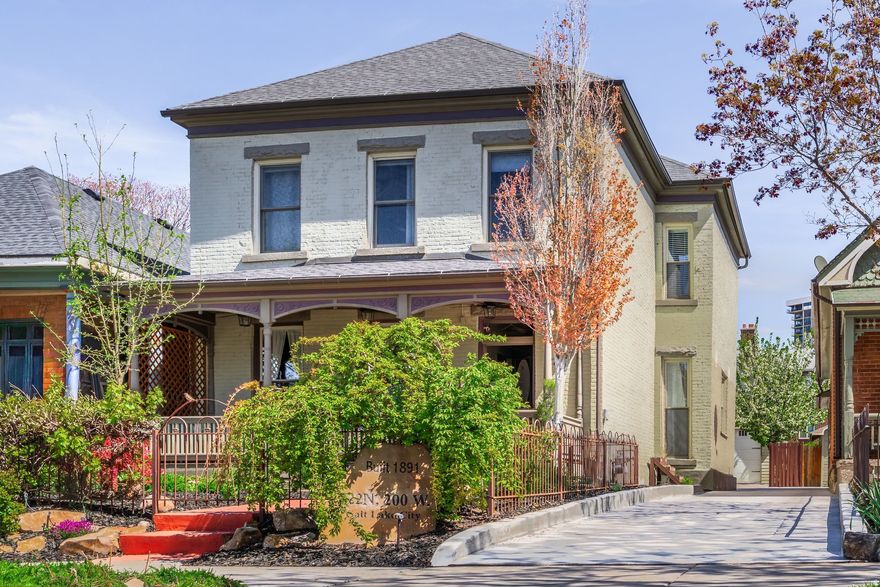 Located on a picturesque, tree-lined street in Salt Lake City's vibrant Marmalade neighborhood, this beautifully restored two story residence offers a rare blend of historic character and modern refinement. Thoughtfully renovated from top to bottom, inside and out, the home has been carefully preserved to honor its architectural heritage while seamlessly incorporating contemporary comforts. The home reveals its timeless appeal upon entry. The front sitting room is defined by soaring twelve foot ceilings and elegant built-ins that create both presence and warmth. Just beyond, the dining room features exposed brick, adding texture and authenticity to the gathering space. The kitchen has been thoughtfully reimagined with custom cabinetry, bar seating for three, stainless steel appliances and a generous walk-in pantry, offering both beauty and functionality. A stylish half bath with exposed brick detail and a well designed laundry and mud room with additional cabinetry complete the main level.Upstairs, the spacious primary suite serves as a private retreat, complemented by a custom double vanity and Euro glass shower. Two additional bedrooms and a Jack and Jill bath provide flexibility for family or guests. The lower level offers a substantial storage area along with updated mechanical systems, including HVAC, electrical, PEX plumbing and a water filtration system, delivering peace of mind and long term value. Outdoors, the backyard is a true urban sanctuary, anchored by a covered stamped concrete patio ideal for entertaining or quiet evenings at home. The oversized two-car garage is enhanced by a finished office above, complete with mini split HVAC, LVP flooring and recessed lighting. The garage is also EV charger ready. Located just minutes from the Delta Center and within close proximity to Salt Lake City's dining, cultural attractions and freeway access, this exceptional home offers a rare opportunity to experience historic charm elevated by thoughtful modern living.