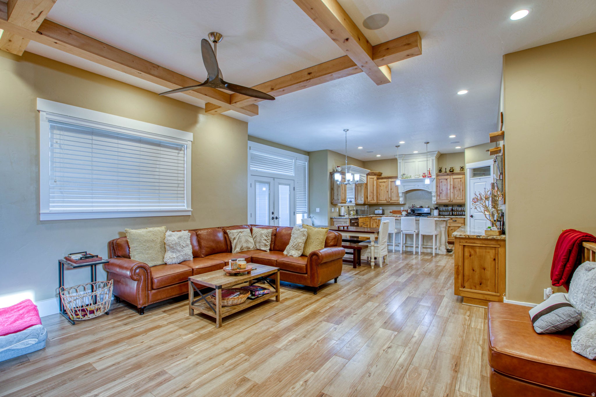 Spacious living area featuring wood-finish flooring, exposed ceiling beams, and recessed lighting