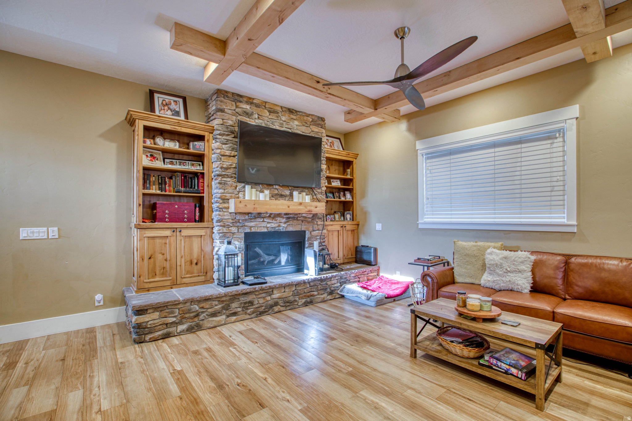 Stone-faced fireplace with a wood mantel, integrated television, and built-in wood cabinetry