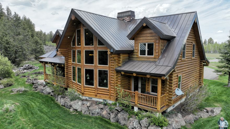 Fully Furnished Custom-Built Log Cabin Near Blackfoot Reservoir - Year-round county paved road access - 3,466 +/- square feet, 5 bedroom, 3 1/2 bath custom-built log cabin built 2013-2014 - Overhead power was pulled to the property replacing the off-the-grid capability - A Smart Meter allows the 4 solar panels to backfeed grid - Deep bay 54' x 34' workshop with 2 RV doors and 65 amp electric car charging outlet - 22' x 36' Detached garage will be repaired this winter - Screwless metal roof replaced in 2024 - 2 efficient stone wood burning fireplaces with abundant firewood included - Mountain Land KitchenAid stainless steel appliances, gourmet Wolf range and Sub-Zero refrigerator freezer - Solid wood handcrafted Amish furniture, gun safe, pool table, Traeger smoker, and Weber grill - Thick granite countertops and backsplash - Slate shower and tub surrounds - Flooring: Rough cut finish walnut, slate, stone, and carpet - 3 Pressurized accumulator tanks, water softener, and tankless hot water heater - 110v hot tub on upper-level covered deck - 34+/- acres west of Government Damn Road will be split off 80-acre parcel prior to closing -- Tucked in the tall evergreens near Blackfoot Reservoir, this fully furnished custom-built log home, the Coeur d'Alene, with tongue and groove construction, offers a turnkey high-country retreat or year-round residence. With handcrafted solid wood Amish furniture throughout, this beautifully appointed, 3,466 +/- square foot, five-bedroom, three-and-a-half bath cabin built in 2014 currently sits on eighty acres with a detached garage and shop. Overhead power was pulled to the property this fall, replacing the off-the-grid capability, and a Smart Meter was installed outside the deep bay workshop to allow the solar panels to backfeed the grid. This could provide credits on your electricity bill. The landowner will split off this homestead of approximately thirty-four acres of ground west of Government Dam Road prior to closing.  The open floor plan with vaulted ceilings and natural light streaming in through the many expansive windows creates a welcoming glow against the warm wood beams and beautiful, rough-cut finish walnut hardwood flooring throughout. In the fall, the lush evergreen carpeted ridge is particularly vibrant against the golden leaves and white trunks of the aspens. Painted kitchen cabinets and coordinating backsplash provide a fresh, contemporary vibe, and the decorative ceiling logs are the perfect accent to meld the two. Boasting Mountain Land KitchenAid stainless steel appliances, a gourmet Wolf range, and a Sub-Zero refrigerator freezer, thick granite countertops with rough edge finish, and backsplash throughout the home. Slate tub and shower surrounds are complemented by slate and stone flooring in the bathrooms and carpet in the upstairs bedrooms. The master bath subfloor is heated for added comfort. At the end of the day, enjoy a nice, relaxing soak in the clawfoot tub and curl up by one of the wood-burning fireplaces with a good book.  The 54' x 34' deep bay workshop with two RV doors provides plenty of room to park and store your vehicles, RV, boat, and ATVs, and work on projects at your leisure, and the asphalt driveway offers ample parking to accommodate your guests' vehicles. A 65-amp electric car charging outlet was recently installed in the workshop. Two efficient and reinforced stone wood-burning fireplaces are focal points and poised for heavy mounts to be hung securely. Abundant firewood is stacked inside the shop and at your disposal.  Experience the serenity of the outdoors year-round on the covered decks and fireside pavilion picnic area. The main level covered front porch is the full length of the cabin and provides two separate entrances and ample space for greeting guests and seating. The covered deck off the kitchen is plumbed for propane and equipped with a Weber grill and Traeger smoker. Enjoy a little peace and possibly wildlife viewing on the master bedroom de