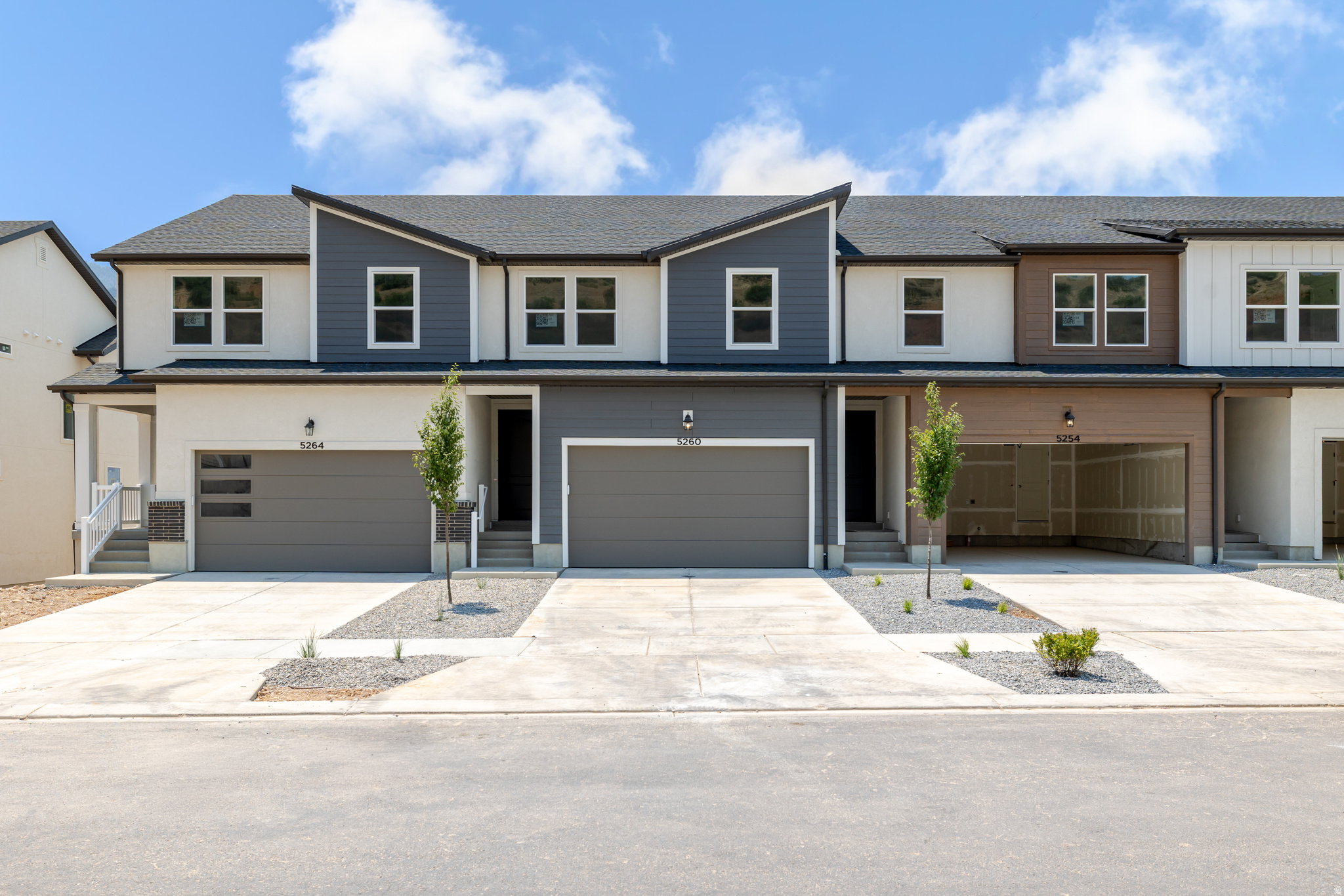 Contemporary townhome facade featuring multi-tone siding, attached single-car garage, and a covered entry porch