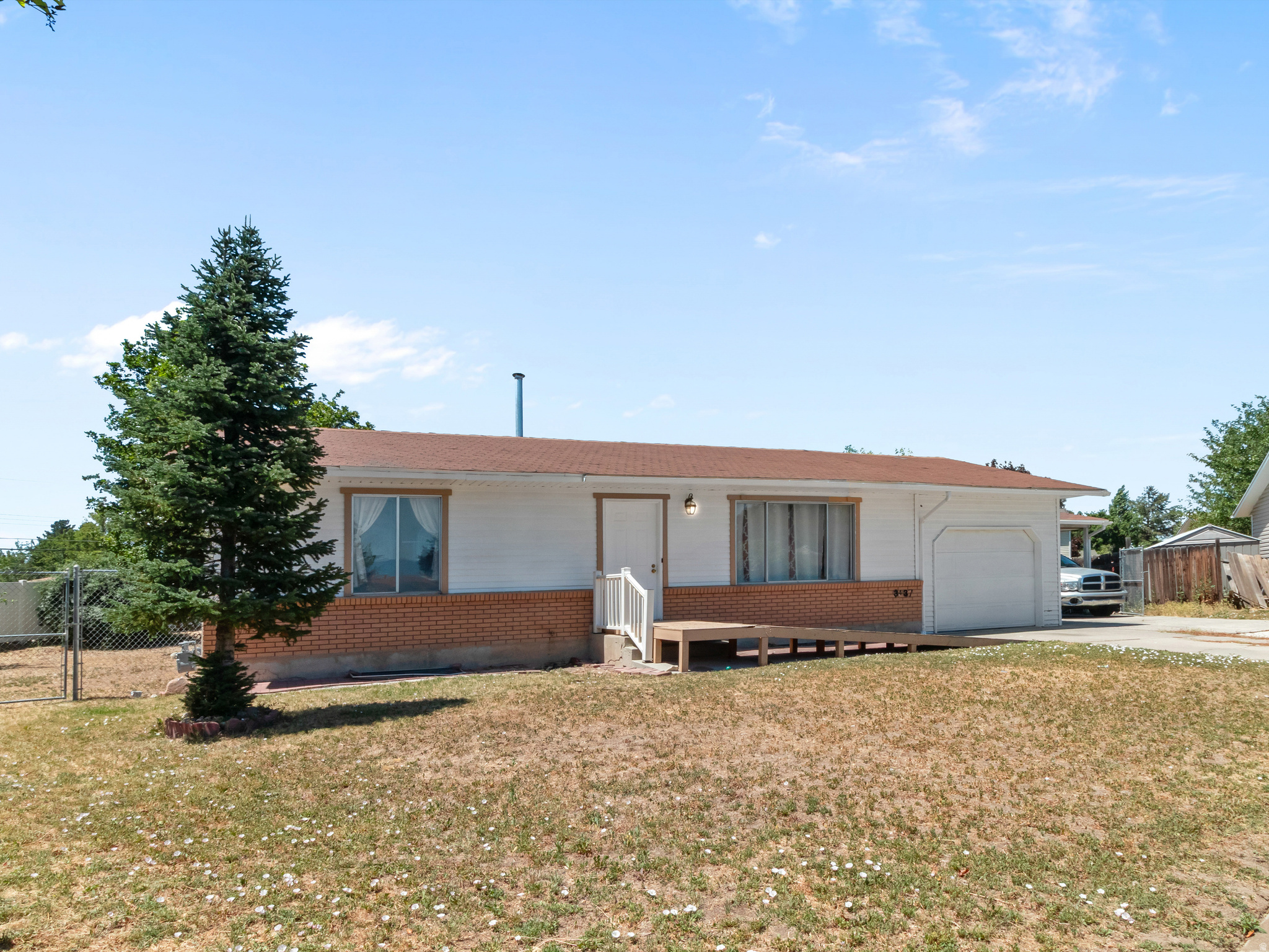 Ranch-style exterior featuring white siding, a brick facade, and a brown shingle roof