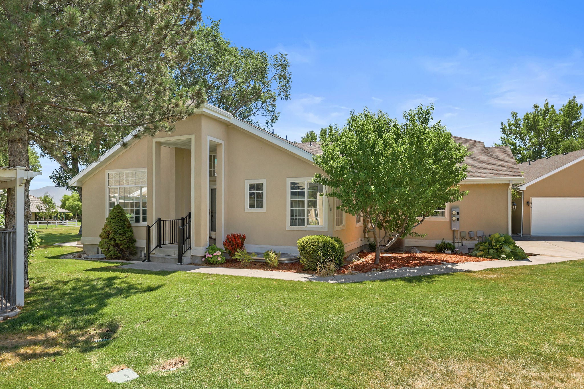 Neutral-toned stucco exterior with a prominent entryway featuring black metal railings