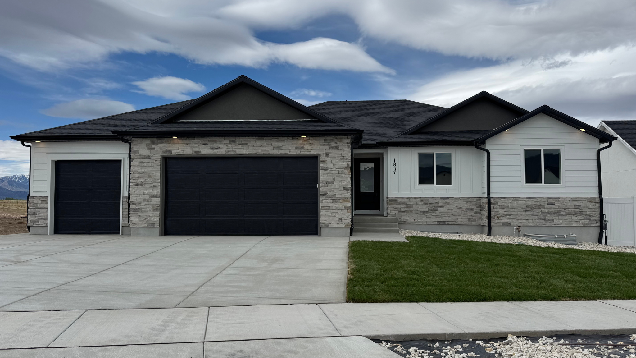 Contemporary exterior featuring a split-level stone facade and white horizontal siding