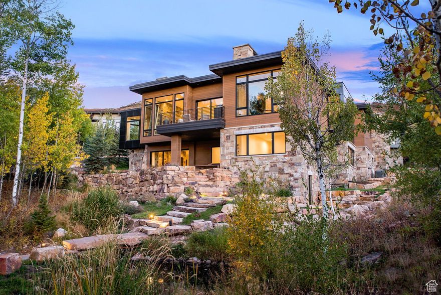 An extraordinary opportunity to own one of only four single-family residences in the coveted Enclave at Sun Canyon. This custom home, designed by renowned architect Michael Upwall, was envisioned to blend seamlessly with its surroundings, embracing the natural beauty of the alpine landscape. Thoughtfully crafted with organic materials-stone, wood siding, and live roof accents-the design creates a timeless connection to the land while maintaining a contemporary aesthetic. Designed to blur the lines between indoor and outdoor living, expansive floor-to-ceiling glass walls invite the outside in, flooding the interiors with natural light and breathtaking views of the surrounding canyon and Deer Valley. A meticulously crafted water feature weaves through the backyard, enhancing the serene ambiance with the soothing sounds of flowing streams and sculptural rock formations. The main level is thoughtfully curated for both comfort and grandeur, featuring a spacious great room with a dramatic stone fireplace, gourmet chef's kitchen with butler's pantry, open dining area, and main-level deck with built-in BBQ. A private study and a secluded primary suite complete the main floor, offering a tranquil retreat. The lower level provides a generous family room with wet bar and three guest bedroom suites, each designed for privacy and relaxation, including their own bathrooms. The backyard oasis offers multiple spaces to unwind, including a concrete patio with hot tub and a fire pit section next to your private pond surrounded by mature landscaping. A three-car expansive garage provides ample storage for vehicles. For all your toys and outdoor gear, take advantage of an extra-large storage room to keep everything organized. Step outside to find world-class hiking and biking trails right at your doorstep through the community's private trailhead or enjoy the charm of Park City's Historic Main Street, just 15 minutes away, offering fine dining, shopping, and cultural events. Salt Lake City International Airport is only 30 minutes away, making travel effortless.