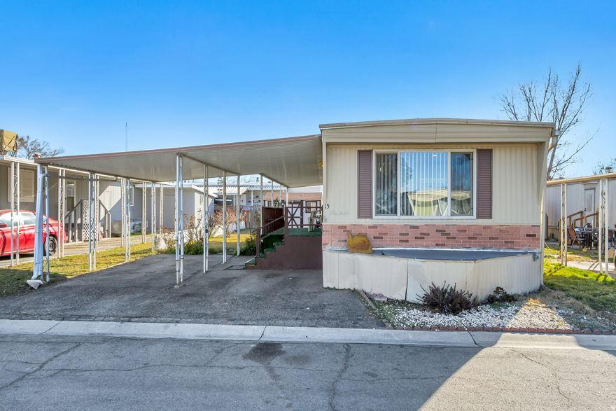 Charming 2-bedroom, 1-bath mobile home offering approximately 900 sq ft of comfortable living space. This well-laid-out home features a bright living area with large front windows that bring in plenty of natural light. The covered carport provides convenient parking and protection from the elements, with easy access to the home. Exterior steps and a small raised entry add character, while the low-maintenance yard offers space for light gardening or outdoor seating. Located in a quiet mobile home community, this property is a great opportunity for affordable living, downsizing, or a seasonal retreat.