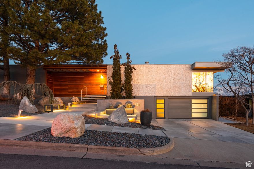 A classic Mid-Century home typically offers a private front, with a glass-walled rear. The previous owner of this home collaborated with Red Butte Garden's horticulturist to meticulously select foliage suitable for the yard. Notably, the home boasts a prized cactus plant transported from Arizona by the homeowner himself. This Eduard Dreier home embodies the essence of Mid-Century Modern architecture, featuring a new steel floating staircase leading to the front door. It is flanked by a solid travertine rock wall on one side and a solid minimalist brick wall on the other. A cantilevered roofline extends the entire length of the rear, providing multiple seating areas to admire the surrounding mountains, canyons, and trails. External walls and ceilings extend outward, resembling the wings of a child's imagination. The natural balance and beauty of the structure evoke a sense of wonder, prompting the question of why every building is not constructed in this manner.  The home has undergone a beautiful renovation, guided by the architectural integrity team of Diamond Phillips. Notable updates include a new steel railings, sea grass wall coverings, a classic shuffleboard painted on the cement floors, and an abundance of greens and florals in the backyard. This outdoor space not only entertains but also provides a calming atmosphere. Floor-to-ceiling windows maximize the views, allowing nature's sounds and movements to be fully experienced. Amidst a snowstorm, the glass walls create a profound sense of tranquility, akin to residing in a treetop. Witnessing the sunrise and sunset, with the moon hovering above, are among my cherished moments and the defining characteristics of this remarkable home.