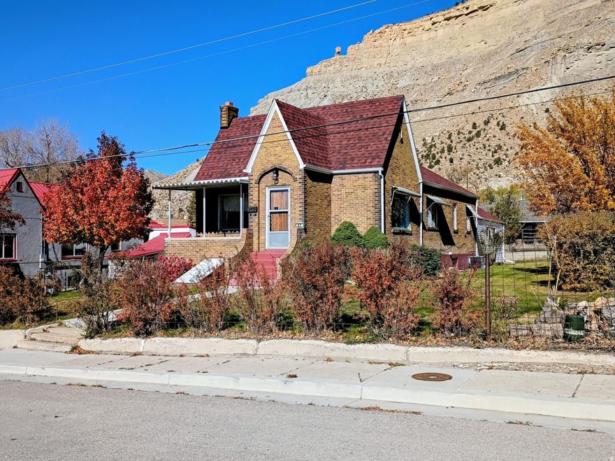 GREAT HOME IN HISTORIC HELPER, UTAH located on a dead-end street. Turn this home into your personal art studio with the beautiful mountains in the background. There are 4-bedrooms, 1.75 bathrooms, 2 car garage with storage on two city lots with alley access. Take a tour of this spacious brick Tudor-style home with over 3,600 square feet. This property offers the perfect blend of privacy and conveniently located a short distance from downtown Helper. The main level of this charming home features two bedrooms and a full bathroom along with built-In storage in the hallway. Additional storage can be found in each bedroom closet, ensuring ample space for all your belongings. Entertain guests in the formal living room, which provides plenty of space for family and friends. Adjacent to this is the formal dining room, perfect for enjoying dinner with loved ones. The eat-in kitchen is a cozy spot for casual meals, equipped with a large walk-in pantry and newer appliances, making it a practical and inviting space for cooking and dining. The expansive family room addition features real hardwood flooring and a stunning rock fireplace with a woodstove insert, ideal for those cooler evenings. With large picture windows in the living and dining rooms, the main level is bathed in natural light, creating a warm and inviting atmosphere. The basement offers 2 additional bedrooms and a 3/4 bathroom with a corner shower with natural light. Relax on the patio and soak in the peaceful surroundings of Helper while appreciating the nearby beautiful rock mountains. Enjoy the view of the famous balanced rock sitting on top of the mountain nearby. The property is home to an apricot tree, apple tree and walnut tree, adding to its charm. A manual sprinkler system helps maintain the lush greenery. The detached two-car garage provides plenty of storage space, ideal for vehicles and outdoor equipment. The home features several updates, including a newer roof and siding on the family room. Tax ID: 1A-1082-0000 is included in the sale. Water shares are included with the sale. Conveniently located near ATV trails, the Helper River walkway and a vibrant arts community. Perfect home for those who love outdoor adventures and cultural experiences. Square footage figures are provided as a courtesy estimate only and were obtained from the Carbon County Tax Records. Buyers are advised to obtain an independent measurement for accuracy.