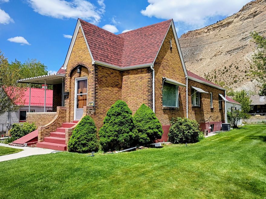 Investment Opportunity! Huge price reduction on this unique home in historic Helper where the movie Salt and Honey was filmed recently. Charming Tudor-style home offers over 3,600 square feet of comfortable living space, along with 3.5 valuable water shares through the Spring Glen Canal Company. Listing includes a large lot to the East that could be used as a garden spot along with alley access to both properties. The main level features two bedrooms, a full bathroom and built-in hallway storage, with additional closet space in each bedroom. A spacious formal living room and large dining room make entertaining easy, while the cozy eat-in kitchen includes newer appliances and a generous walk-in pantry. The standout family room addition boasts real hardwood flooring and a striking rock fireplace with a woodstove insert-perfect for cozy evenings. Large picture windows in the living and dining areas offer natural light, creating a warm and inviting atmosphere. Downstairs, the basement offers two additional bedrooms and a  bathroom with a corner shower and natural light. Outside, enjoy peaceful surroundings from the patio, with scenic views of Helper's iconic red rock landscape. The property also features: Mature apricot, apple, and walnut trees, a manual sprinkler system for easy yard maintenance, a detached two-car garage with ample storage. Updates include a newer roof and siding on the family room. A new gas meter was recently installed by the gas company. Located near ATV trails, the Helper River walkway and a thriving local arts scene. This home is ideal for those who appreciate both outdoor adventure and cultural charm. Tax ID: 1A-1082-0000 included with the listing. Square footage figures are provided as a courtesy estimate only and were obtained from the Carbon County Tax Records. Buyers are advised to obtain an independent measurement for accuracy.