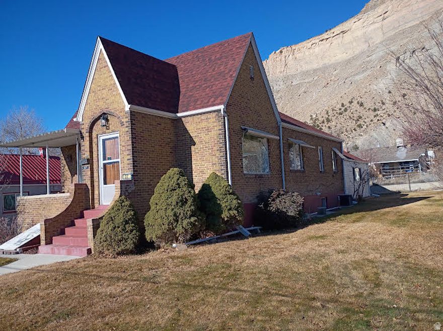 GREAT HOME IN HISTORIC HELPER, UTAH located on a dead-end street. Turn this home into your personal art studio with the beautiful mountains in the background. There are 4-bedrooms, 1.75 bathrooms, 2 car garage with storage on two city lots with alley access. Take a tour of this spacious brick Tudor-style home with over 3,600 square feet. This property offers the perfect blend of privacy and conveniently located a short distance from downtown Helper. The main level of this charming home features two bedrooms and a full bathroom along with built-In storage in the hallway. Additional storage can be found in each bedroom closet, ensuring ample space for all your belongings. Entertain guests in the formal living room, which provides plenty of space for family and friends. Adjacent to this is the formal dining room, perfect for enjoying dinner with loved ones. The eat-in kitchen is a cozy spot for casual meals, equipped with a large walk-in pantry and newer appliances, making it a practical and inviting space for cooking and dining. The expansive family room addition features real hardwood flooring and a stunning rock fireplace with a woodstove insert, ideal for those cooler evenings. With large picture windows in the living and dining rooms, the main level is bathed in natural light, creating a warm and inviting atmosphere. The basement offers 2 additional bedrooms and a 3/4 bathroom with a corner shower with natural light. Relax on the patio and soak in the peaceful surroundings of Helper while appreciating the nearby beautiful rock mountains. Enjoy the view of the famous balanced rock sitting on top of the mountain nearby. The property is home to an apricot tree, apple tree and walnut tree, adding to its charm. A manual sprinkler system helps maintain the lush greenery. The detached two-car garage provides plenty of storage space, ideal for vehicles and outdoor equipment. The home features several updates, including a newer roof and siding on the family room. Tax ID: 1A-1082-0000 is included in the sale. Water shares are included with the sale. Conveniently located near ATV trails, the Helper River walkway and a vibrant arts community. Perfect home for those who love outdoor adventures and cultural experiences. Square footage figures are provided as a courtesy estimate only and were obtained from the Carbon County Tax Records. Buyers are advised to obtain an independent measurement for accuracy.
