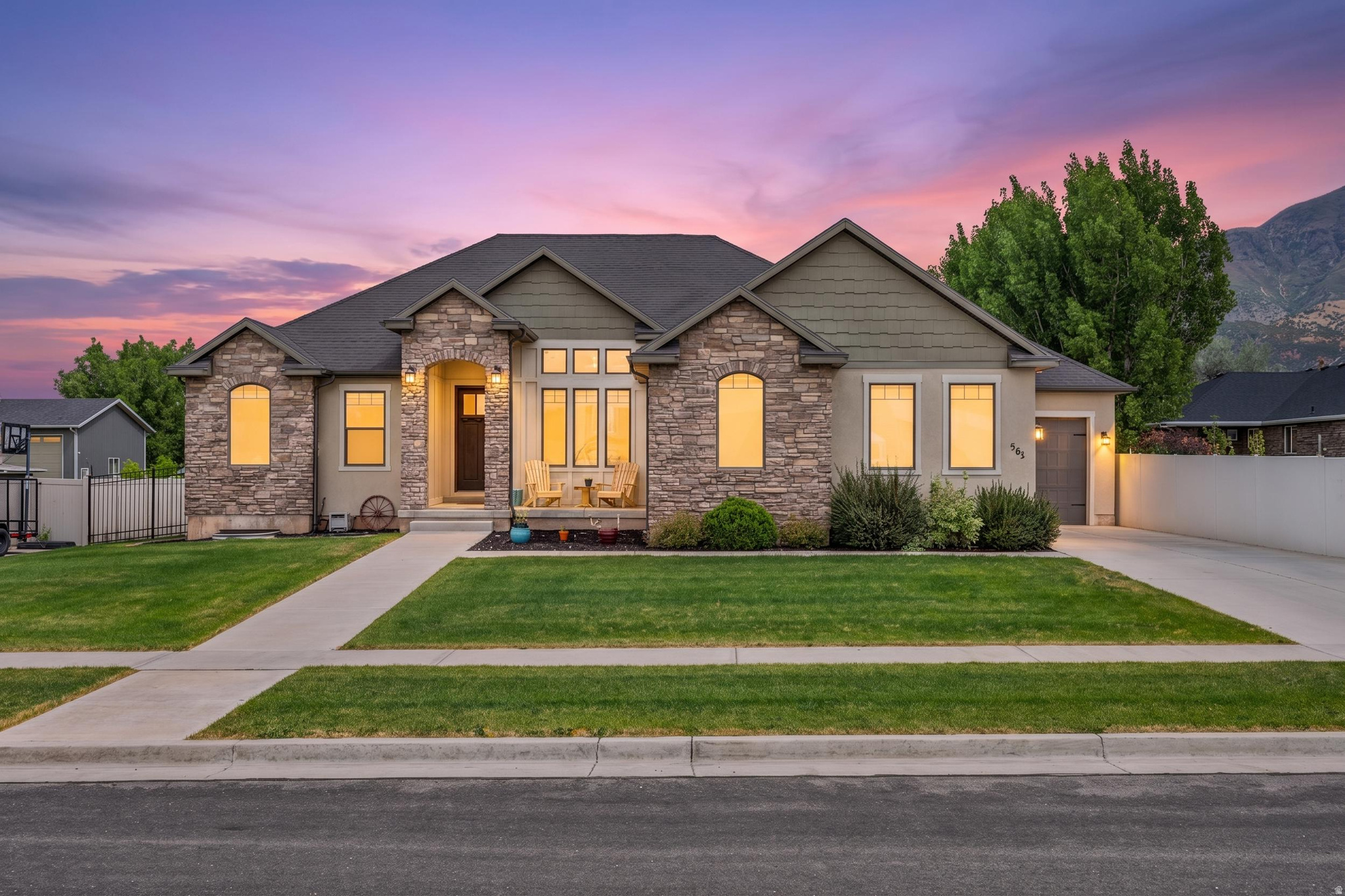 Stone and stucco exterior featuring a covered front porch, an attached garage, and a concrete driveway