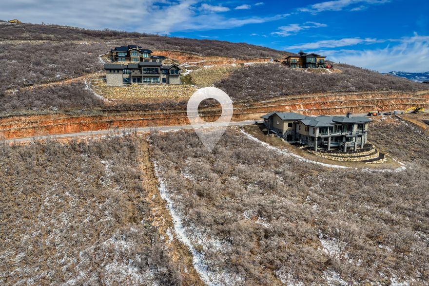 Arguably the most compelling homesite opportunity currently available in Golden Eagle, this coveted downhill lot borders protected open space to the north and sits along one of the community's most protected view corridors--creating rare privacy while capturing sweeping vistas of Jordanelle Reservoir, Deer Valley, Park City Mountain, The Canyons, and the iconic Mount Timpanogos. With no neighboring homes to the north, the setting enjoys an exceptional sense of space and seclusion while preserving the expansive views that define Golden Eagle living.  The coveted downhill orientation allows a future residence to step naturally with the terrain, maximizing view corridors from every level while creating ideal opportunities for walk-out living spaces, expansive decks, and dramatic mountain architecture designed to embrace the surrounding landscape.  Included with the property are stamped and approved architectural plans for a stunning 6,610-square-foot luxury residence, offering a rare opportunity to bypass the lengthy design and architectural approval process and move more quickly toward construction.  Golden Eagle spans more than 600 acres, with over 25% preserved as open space. Residents enjoy miles of private hiking and biking trails and will soon gather at the planned community clubhouse featuring indoor and outdoor gathering spaces, a kitchen, and a fire pit. A restrictive nightly-rental policy helps preserve a quiet residential atmosphere and a true sense of community.  Located just 15 minutes from the new Deer Valley East Village, minutes to Park City's Historic Main Street, and only 35 minutes from Salt Lake City International Airport, this homesite offers an exceptional opportunity to build a legacy mountain retreat surrounded by some of Park City's most iconic scenery.
