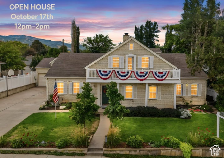 Two-story masonry exterior featuring a covered upper-level balcony, gable roofline with chimney, shuttered windows, and…