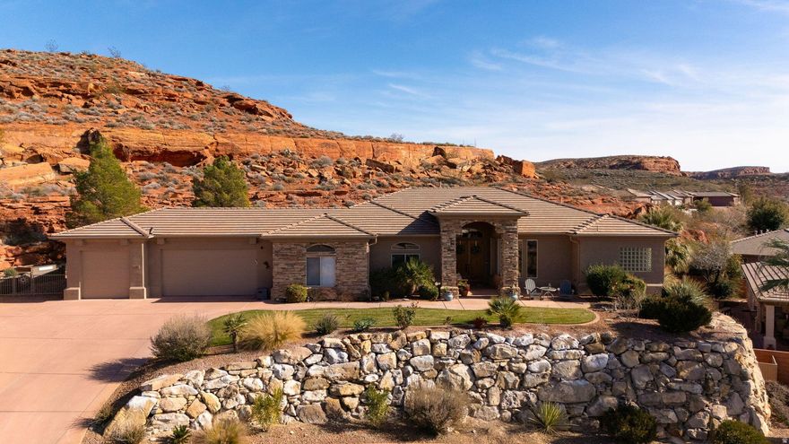 Nestled in Paradise Canyon, this beautiful home is surrounded by striking red rock formations and a peaceful canyon-like setting, while remaining close to shopping, dining, and daily conveniences. Enjoy direct access to nearby walking and biking trails and take in Southern Utah's natural beauty. Inside, the home offers abundant natural light, high ceilings, and a cozy fireplace. The open kitchen features warm wood cabinetry, generous counter space, and an island that flows into the dining area-ideal for entertaining. The spacious primary suite includes a relaxing en-suite bath with dual vanities, soaking tub, and walk-in shower. A covered patio provides the perfect place to unwind and enjoy the scenic views.