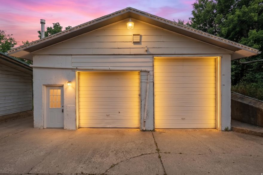 Spacious detached garage storage solutions offering exceptional functionality and versatility, featuring two oversized overhead doors for easy access, a separate pedestrian entry and stylish exterior sconce lighting for added curb appeal. Inside, enjoy expansive concrete floor space, durable concrete walls, exposed wood beam ceilings, bright fluorescent lighting, and convenient utility access. 24X7 access.