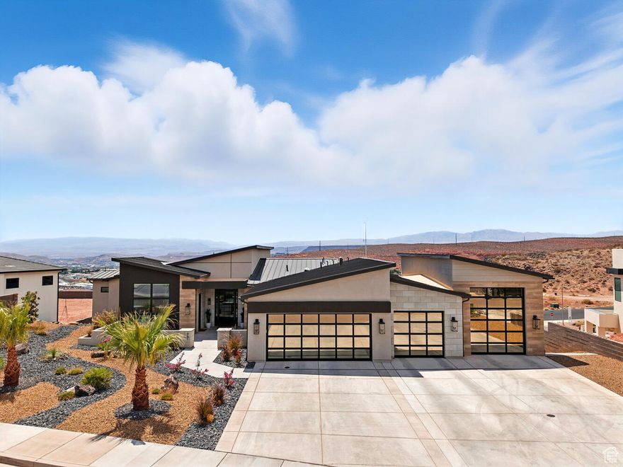 A designer-crafted sanctuary where every finish is curated and wide-open views make every sunset feel like it's yours alone. From this hilltop retreat, ride directly from your home to the Red Cliffs trails, explore the mountains, or unwind by your resort-style pool. Contemporary architecture and low-maintenance landscaping welcome you home. The front patio opens to a bright foyer and more than 5,000 square feet of designer-finished space. Warm alder trim, Rustica doors, custom grass-cloth walls, and art-quality lighting tie the interiors together. Every bedroom is en-suite, and with an optional furnishing package, you could have the whole home professionally decorated and move-in ready.  The floor plan puts your main living areas upstairs to take in the panorama over St. George and the mountains. The great room is open and comfortable, centered on a floor-to-ceiling fireplace and sliding doors to a wide view deck.  The kitchen is built for cooking and gathering, with a huge waterfall-edge island, top-tier appliances, and loads of storage. A bonus pantry adds a second sink and ice maker for every delightful concoction you create. Also upstairs, the primary suite frames miles of scenery and opens to the deck. A private sitting area offers space to unwind. The primary bath brings together stone and wood, an oversized shower, a freestanding tub, and thoughtful storage. A separate-entry casita on this level works as a guest suite or office, finished with custom wall coverings and its own full bath.  Downstairs expands your options even more. A quiet reading nook tucks under the stairs. The lower living room connects bedroom suites, a home gym, and private office, with walkout access to the covered patio and pool. A built-in bar with an ice maker and beverage fridge keeps snacks and drinks handy, alongside a nearby powder bath.  Outside is set up for all-day lounging and easy entertaining. The 18x31' saltwater pool is 4 ft deep with a shamu shelf, hot tub, and an integrated cover, all wrapped by a broad sundeck and privacy walls. An outdoor shower pavilion, shaded dining patio, turf lawn, and a large side yard make it simple to spread out. Sunset color pours across the mountains every evening. A 4-car RV garage holds ATVs, gear, and everything else you bring along. From your hilltop perch on the Middleton Black Ridge, you have direct access to the Red Cliffs Conservation Area and quick trips into town, the best of both worlds for trail days, quiet nights, and easy hosting. The perfect mix of design, function,and location, ready for what you love to do