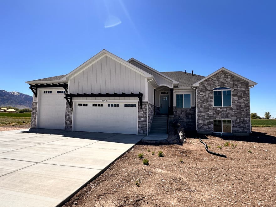 This stunning, custom-built residence sits on a spacious half-acre+ lot and delivers the best of Northern Utah living - breathtaking Wasatch Mountain views to the east and unforgettable sunsets to the west. The thoughtfully designed floor plan features a main-level master suite - 3 bedrooms, and 2 full bathrooms.  An additional 23 bedrooms, a bathroom, and a large open gathering space ready to be finished in the basement - offering incredible flexibility to grow into the space. At the heart of the home, the welcoming kitchen impresses with custom cabinetry, quartz countertops, an oversized island, and stainless steel appliances. The open-concept living area flows effortlessly onto a covered, south-facing deck - perfect for shaded entertaining, morning coffee, or quiet evenings year-round. Car enthusiasts and outdoor adventurers will love the oversized 3-car garage, complete with a 12' door to accommodate all your toys, RVs, and equipment. This is more than a home - it's a lifestyle. Schedule your private showing today.