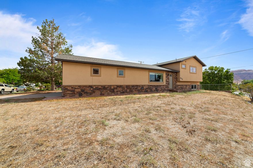 Spacious tri-level with panoramic views - This 4-bedroom, 3-bath home blends convenience and tranquility, perched on Moab's southwest edge with sweeping views over town. Enjoy quick access to shops, dining, and the vibrant arts scene, yet come home to peaceful nights under starlit skies. The main-level kitchen offers direct entry from the oversized garage or north-facing front walk and flows into the dining and living areas. Step out to a covered patio and fully fenced backyard-ideal for gatherings, gardening, or unwinding after a day's adventure. The lower level features two bedrooms, a full bathroom, a dedicated laundry room, and a flexible space perfect for a playroom, office, studio storage, or media nook. Upstairs, you'll find a third bedroom and full bath, along with the spacious primary suite boasting a walk-in shower, jetted soaking tub, walk-in closet, and private views of the surrounding red rock landscape. Offered with tasteful updates inside and central vac