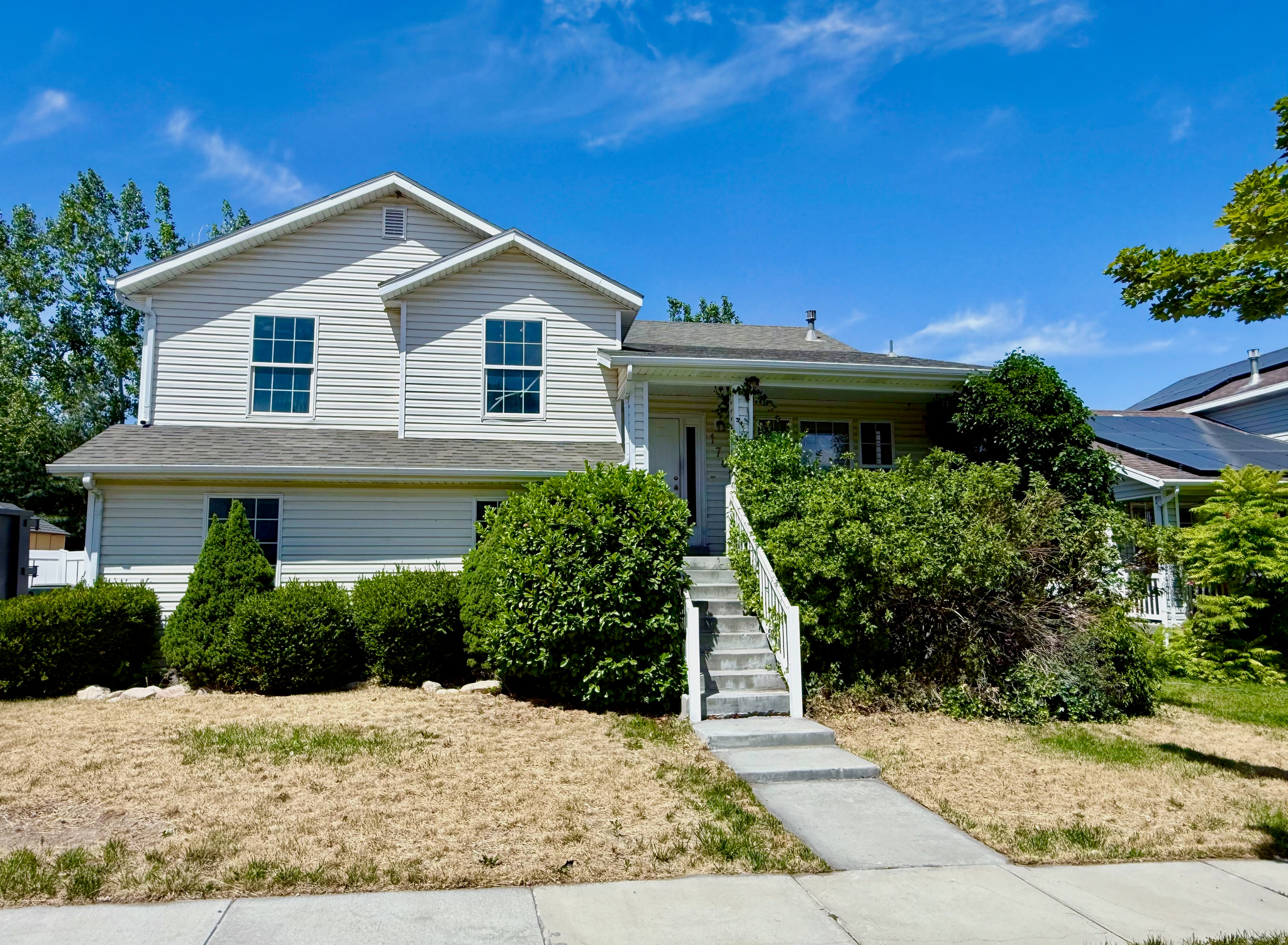 Two-story residence featuring light-colored siding, a covered porch entry, and a concrete pathway