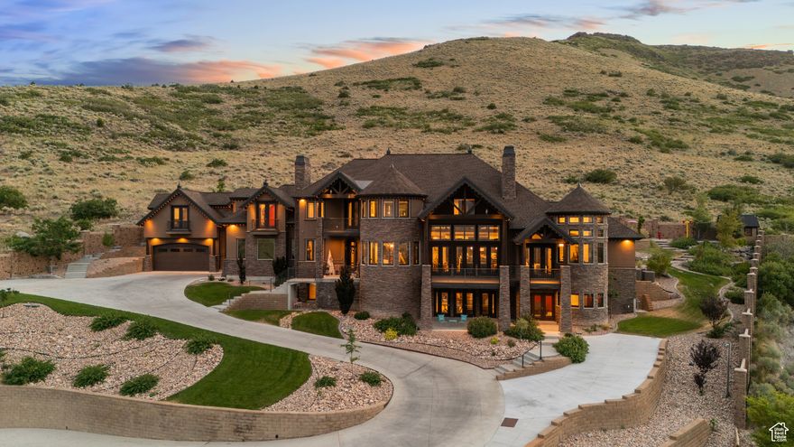Exquisite Herriman Estate with Panoramic Views, Dual Mother-in-Law Suites, and Unmatched Amenities.   Elevate your lifestyle in this extraordinary 10,845 sq ft custom estate, perfectly positioned on 1.12 acres in the prestigious Secret Canyon Circle. Enjoy sweeping, unobstructed mountain and valley views from nearly every room, and retreat to a private, fenced backyard oasis with a splash pad, built-in trampoline, swingset, and low-maintenance landscaping.  This residence is thoughtfully designed for both everyday comfort and grand entertaining. Inside, discover two separate mother-in-law/ADU suites, each with a private entrance and full kitchen, and one with its own laundry, offering unparalleled flexibility for guests or multigenerational living.  The heart of the home is an oversized chef's kitchen featuring a premium 48" dual fuel range with six burners and an infrared griddle, complemented by built-in 30" refrigerator and freezer units for seamless integration and ample storage. A state-of-the-art convection steam oven adds versatility, allowing for healthy, precise cooking with steam and convection modes. This culinary space also includes a hidden walk-in pantry and flows effortlessly to an expansive covered patio with a gas fireplace, stubbed gas BBQ, and hot tub connection-perfect for year-round entertaining.  The main level impresses with soaring two-story ceilings in the main gathering areas, 10-foot ceilings elsewhere, and 8-foot solid wood doors throughout. A sunlit office with a gas fireplace, built in bookcases,  expansive living and dining spaces, and a luxurious primary suite featuring a spa bath, radiant heat floors, and a private deck to savor panoramic valley and mountain views create a serene retreat.  Upstairs, enjoy three spacious en suite bedrooms, each with a walk in closet,  a game room with a slide to the main level, dual staircase access, and a versatile loft.   The walk-out basement is an entertainer's dream, boasting an expansive sports bar with three TVs, a dishwasher, a built-in ice maker, a billiards area, a family room with a fireplace, built in bookcases, an oversized theater room with stadium seating, and a charming kids' playroom under the stairs featuring a custom-painted mural.  Additional highlights include a five-car heated garage, advanced smart-home technology, central vacuum, and premium hardwood flooring throughout. Every detail in this home reflects exceptional craftsmanship and modern luxury.  Schedule your private tour today and experience the unmatched lifestyle this one-of-a-kind Herriman estate offers.