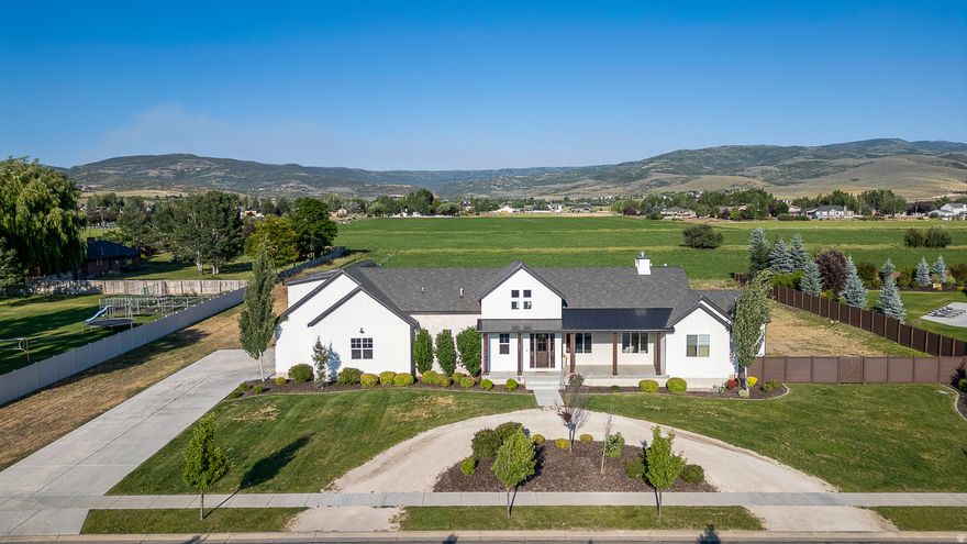 Dreaming of modern farmhouse elegance with true main-level living? Welcome to this exceptional home in Wild Mare Estates, perfectly set on a full acre in Heber City. Thoughtfully designed with a primary bedroom suite on the main floor, this home blends luxury, comfort, and breathtaking mountain surroundings. Step inside to an open, light-filled floor plan featuring soaring vaulted ceilings, a striking floor-to-ceiling stone fireplace, and a dramatic 12-foot panoramic door that seamlessly connects indoor and outdoor living. A spacious loft and versatile bonus area enhance the home's design while offering flexible space for work, play, or relaxation. With 6 bedrooms and 5 bathrooms, there is space for everyone. The fully finished basement is an entertainer's dream, offering a theater room complete with projector and oversized screen, a dedicated exercise room, an expansive recreation area, and a space already prepped for a future kitchen or wet bar. Outside, the fully landscaped front yard showcases a half circular driveway and stunning views of Mount Timpanogos. The partially fenced backyard opens to peaceful farmland with sweeping Uinta Mountain views and features a basketball court and extended patio-perfectly positioned for a future pergola. With plenty of room for a pool, outdoor kitchen, barn, or shop, the possibilities are truly endless. A generous 3-car garage provides ample space for vehicles, toys, and tools. Located just minutes from world-class fishing, skiing, boating, trails, off-roading, and year-round recreation, this home offers the ultimate mountain lifestyle. This is more than a home-it's the one you've been waiting for.