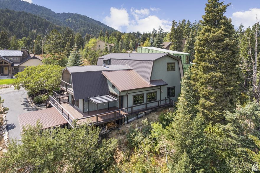 Welcome to Moose Lodge, a rare and updated sanctuary in the pines. Tucked among mature evergreens yet bathed in abundant natural light, this home perfectly blends woodland charm with an airy, sun-filled atmosphere. Named Moose Lodge by its owners, it has long been a peaceful retreat where wildlife wanders through and the beauty of the mountains and sky provide an ever-changing backdrop. A massive wraparound deck and private front courtyard set the stage for outdoor living whether it's morning coffee with the sunrise, long summer dinners under the open sky, or simply curling up with a good book while surrounded by nature. Inside, the open flow between the grand kitchen, great room, and dining area make entertaining effortless, spilling seamlessly onto the deck for gatherings both large and cozy. The home offers thoughtfully designed spaces for connection and relaxation, including a game room and a flexible family/entertainment area. The sun-drenched primary suite feels like its own private retreat, featuring a beautifully renovated and oversized spa-like bathroom and an enormous walk-in closet. Upstairs, a spacious guest suite offers comfort and privacy, while the walkout lower level includes an office, additional bedroom, flex space for hobbies or gatherings, and direct access to a patio and outdoor hot tub. Practicality meets ease with two, south facing driveways, a large two-car garage, and a separate carport, making parking a breeze for residents and guests alike. If you've been searching for a mountain retreat that combines light, space, comfort, and a deep connection to nature, Moose Lodge is waiting to welcome you home. New windows, new doors, new paint, and updated fit and finish throughout make this an ideal full time home or lock and leave vacation getaway.