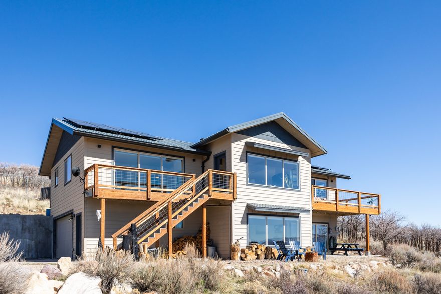 This is a property that asks you to slow down a bit. Part of Rockport Estates near Park City, this home has panoramic views of the ridgeline of the Wasatch back from Canyons Resort to PCMR and Deer Valley, as well as part of the Uintas, as a backdrop, so we're guessing you'll be more than happy to take a beat here. The two story layout is well-designed and cozy, with vaulted ceilings in the main living spaces, an open flow, and the kind of natural light that makes every room feel bright and welcoming. A modern style makes each space feel clean and spacious, and the kitchen is well-appointed with granite countertops and a large island for easy prep and entertaining. Upgrades here go well beyond cosmetic-solar panels, a Tesla Powerwall (capable of keeping the home running for up to 10 days off-grid), an EV charging station, aluminum roof, and four 3,000-gallon water cistern tanks (quadruple the capacity of other homes in the community)-mean this property is as practical as it is beautiful. Outside you'll find decks for lingering with a cup of coffee, a greenhouse for your growing needs, two fire pits for nights spent with friends, a chicken coop for the hens in your life (note: they can be included in the sale), and a natural landscape of scrub oak that keeps things feeling perfectly wild. No matter the level of the home, there's patio access, and RV parking leaves space for your home away from home, should you need it. Residents here can rest easy, as HOA covers road maintenance and water supply, and AG-80 zoning keeps your options open. And, since you're located close to the reservoir, the mountains, and the amenities of Park City, we'd say this one is more than ready for its next lucky owners.  Square footage figures are provided as a courtesy estimate only.  Buyer is advised to obtain an independent measurement.
