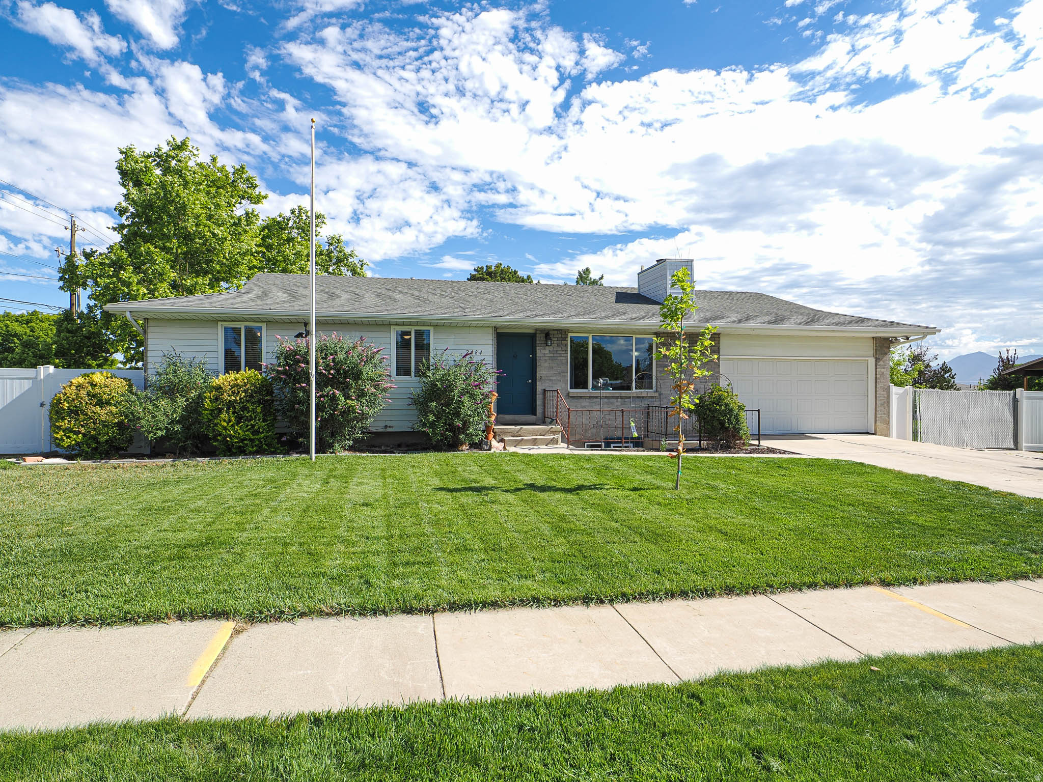 Ranch-style residence featuring a gray shingle roof, light-colored siding, and a blue entry door